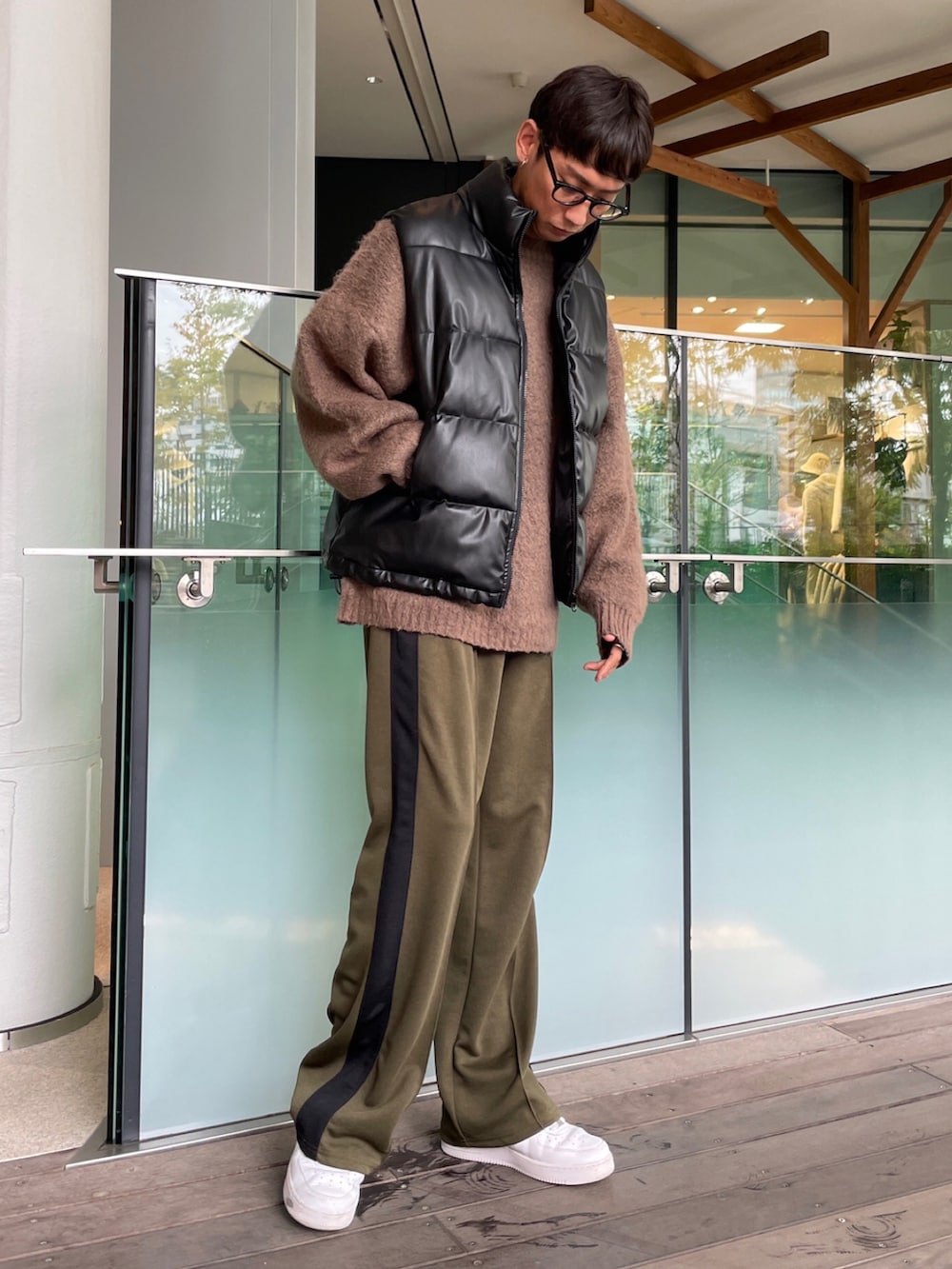 ブラック系のダウンベスト、ブラウン系のニット/セーター、グリーン系のスウェットパンツを着用したメンズの秋コーディネートの2枚目の写真