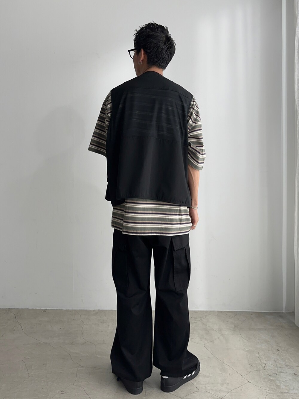 ブラック系のカーゴパンツ、ブラック系のベスト、ブラック系のスニーカーを着用したメンズの夏コーディネートの3枚目の写真