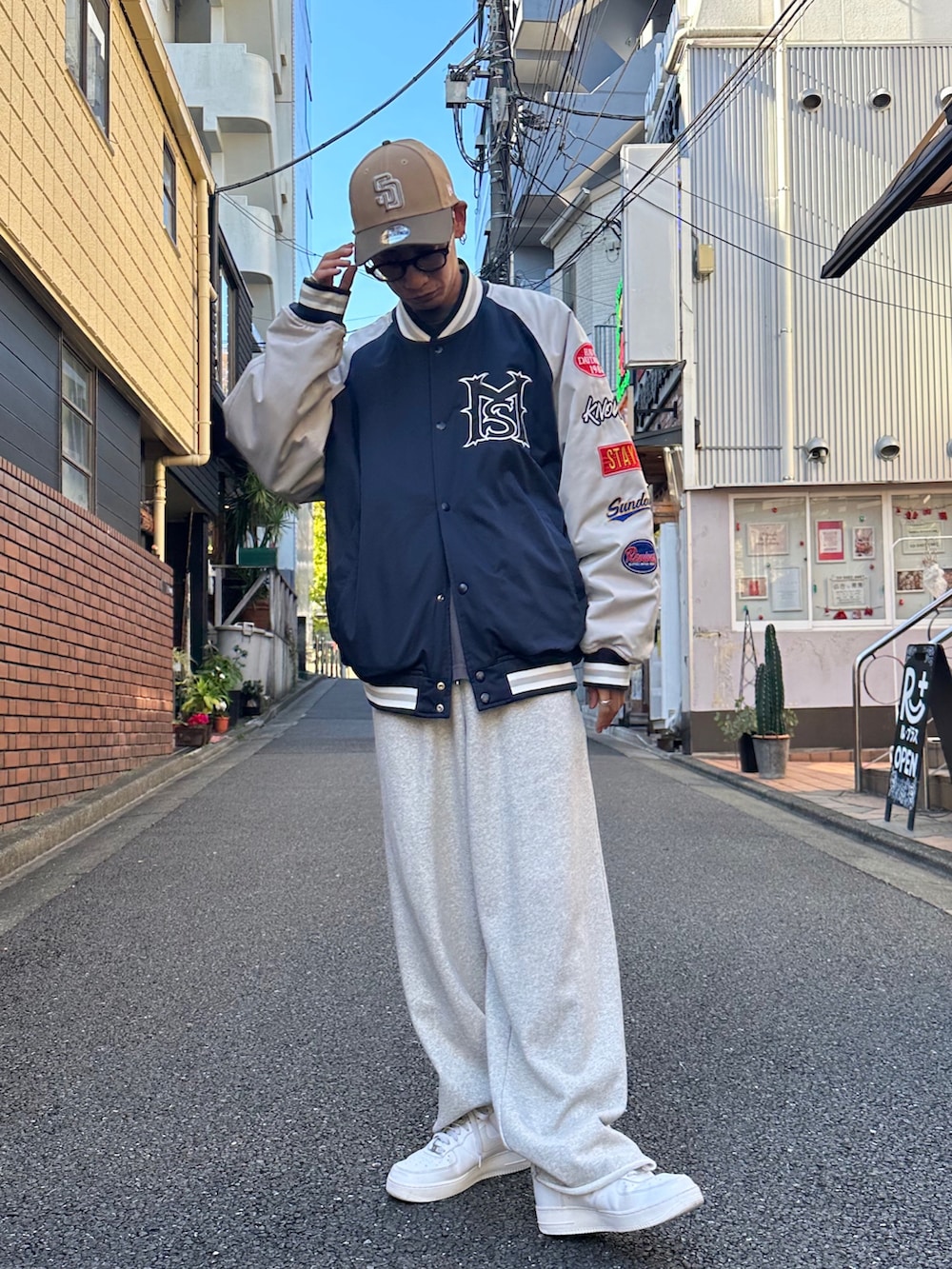 ブルー系のスタジャン、ブラック系のTシャツ/カットソー、ホワイト系のスニーカーを着用したメンズの秋コーディネートの2枚目の写真