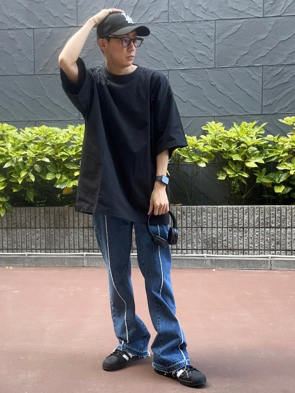ブラック系のTシャツ/カットソー、ブラック系のスニーカー、ブルー系のデニムパンツを着用したメンズの夏コーディネートの2枚目の写真