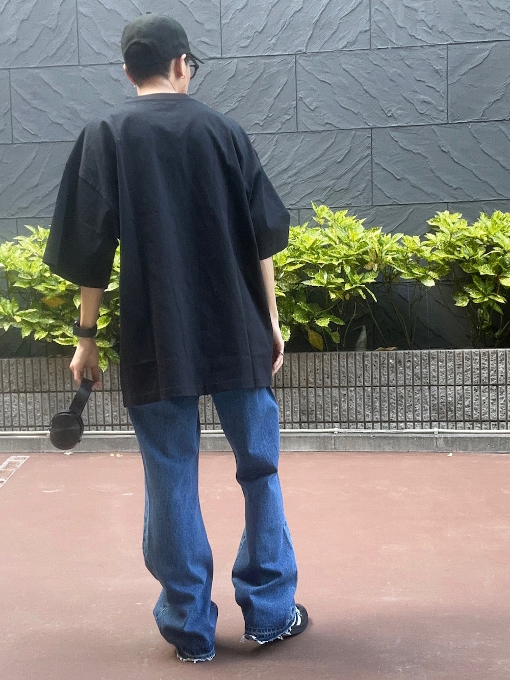 ブラック系のTシャツ/カットソー、ブラック系のスニーカー、ブルー系のデニムパンツを着用したメンズの夏コーディネートの3枚目の写真