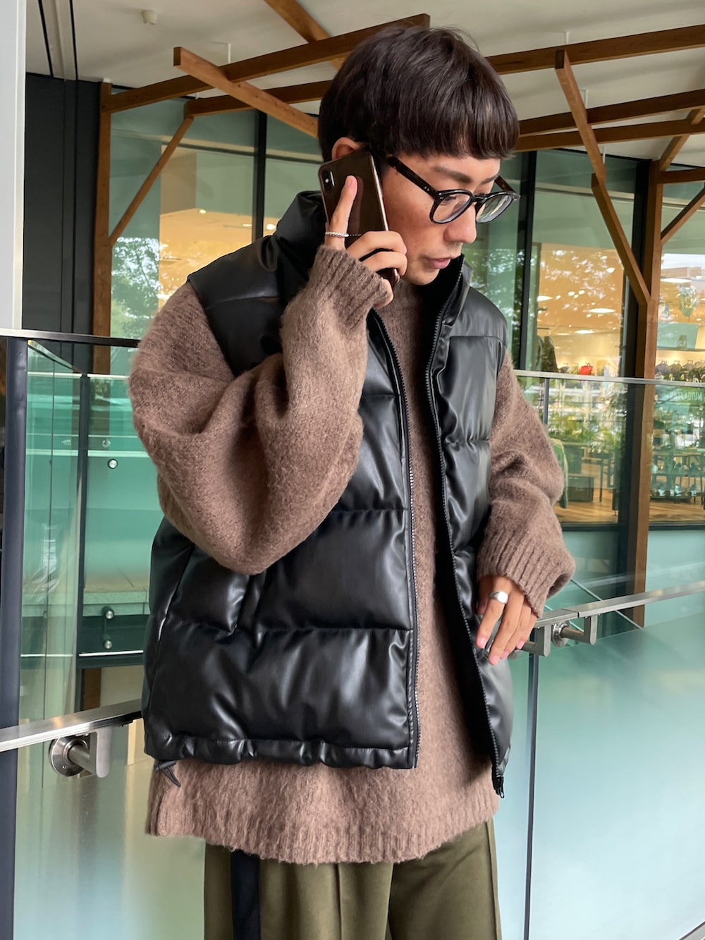 ブラック系のダウンベスト、ブラウン系のニット/セーター、グリーン系のスウェットパンツを着用したメンズの秋コーディネートの4枚目の写真