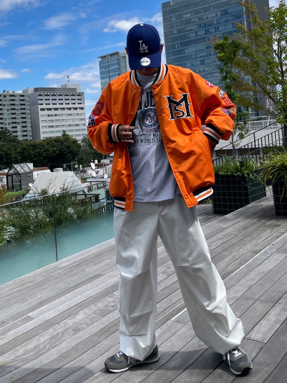 オレンジ系のスタジャン、グレー系のTシャツ/カットソー、ホワイト系のカーゴパンツを着用したメンズの秋コーディネートの2枚目の写真