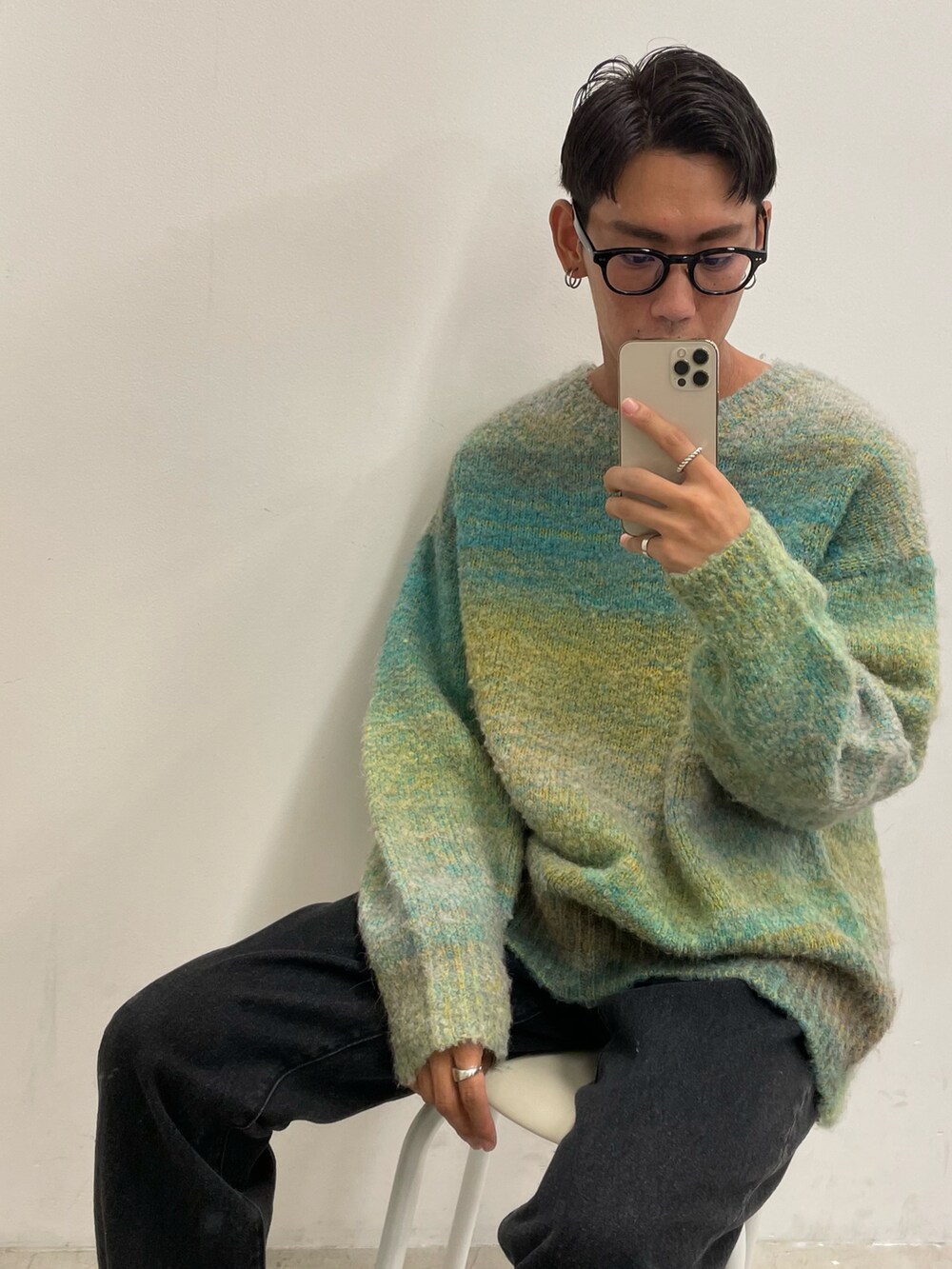 グリーン系のニット/セーター、ホワイト系のタンクトップ、ブラック系のデニムパンツを着用したメンズの秋コーディネートの3枚目の写真