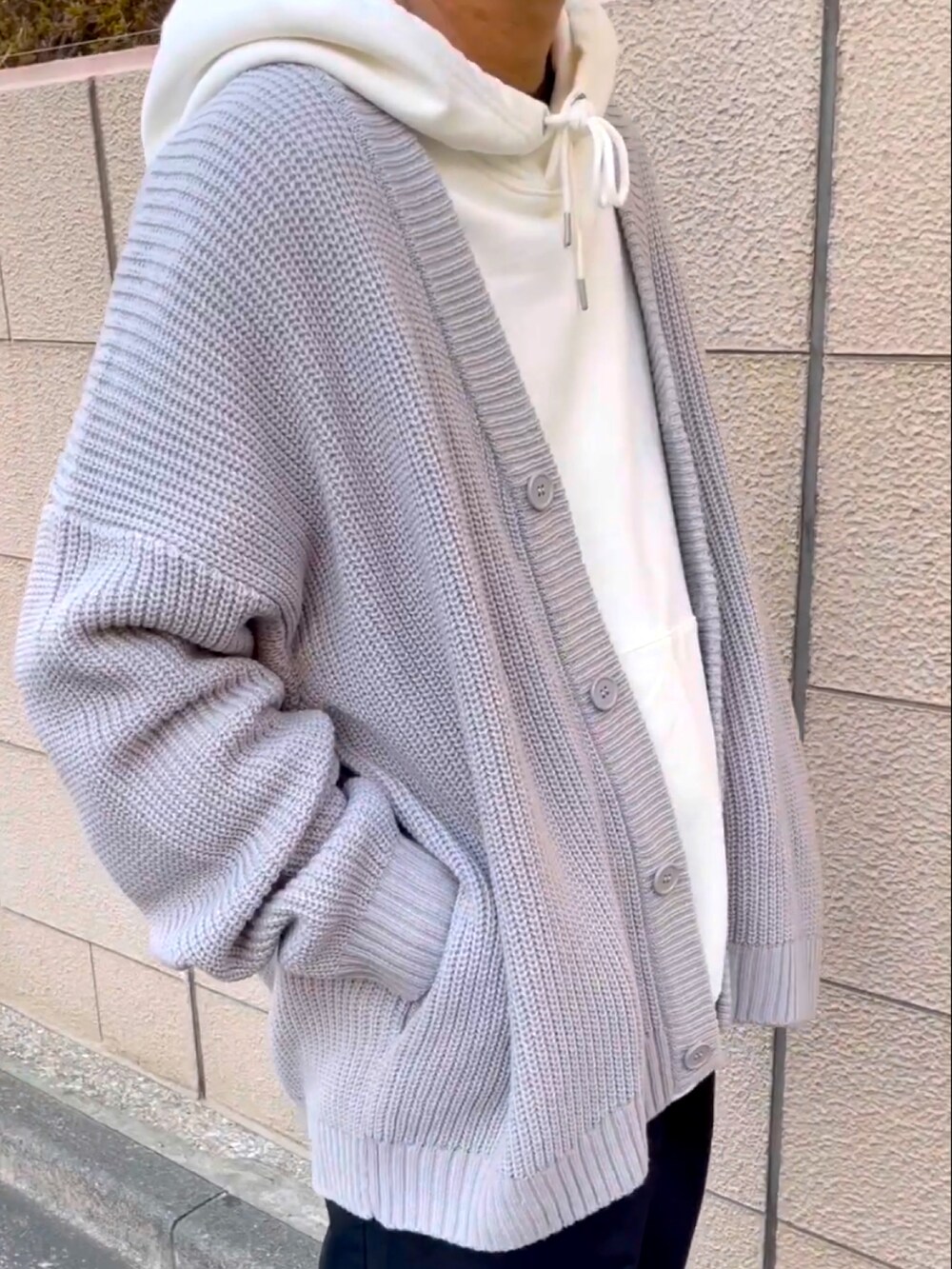 グレー系のカーディガン/ボレロ、ホワイト系のパーカー、ブラック系のチノパンツを着用したメンズの冬コーディネートの3枚目の写真