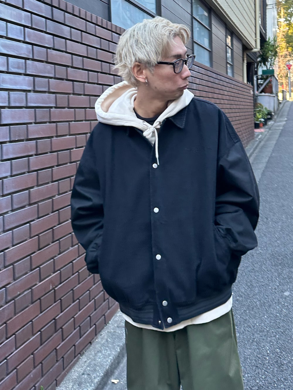 ブラック系のスタジャン、ベージュ系のパーカー、グリーン系のカーゴパンツを着用したメンズの冬コーディネートの5枚目の写真