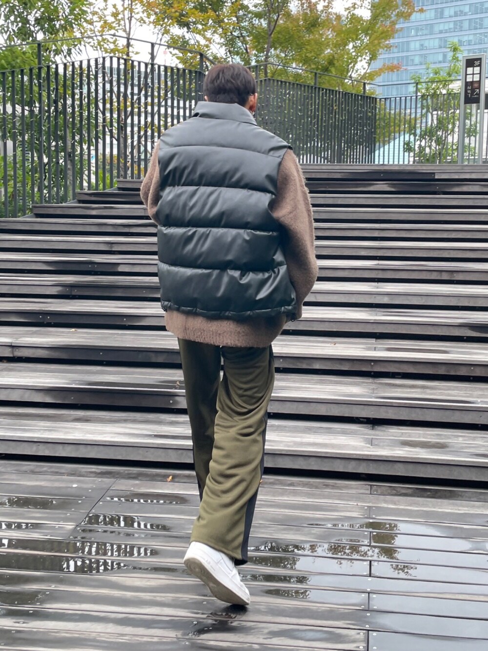 ブラック系のダウンベスト、ブラウン系のニット/セーター、グリーン系のスウェットパンツを着用したメンズの秋コーディネートの3枚目の写真