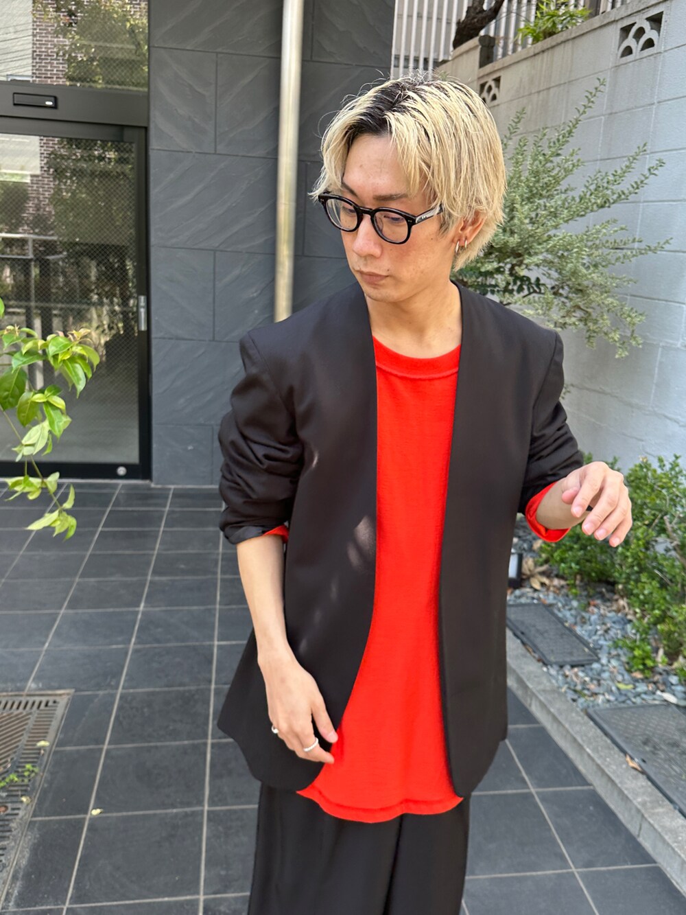 ブラック系のテーラードジャケット、オレンジ系のTシャツ/カットソー、ブラック系のスラックスを着用したメンズの春コーディネートの5枚目の写真