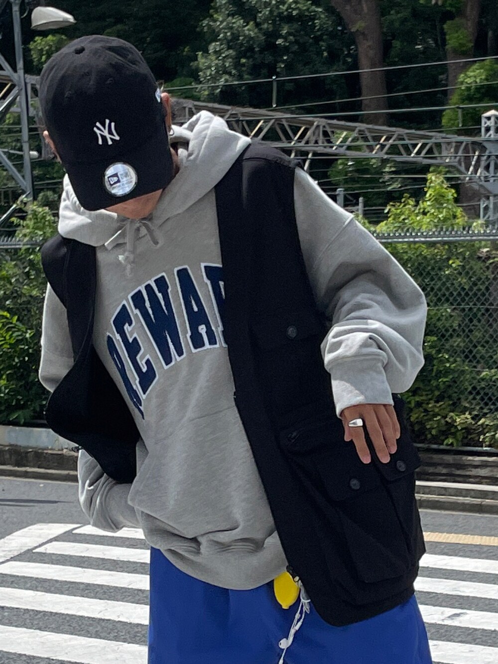 ブラック系のベスト、グレー系のパーカー、ブルー系のチノパンツを着用したメンズの秋コーディネートの2枚目の写真