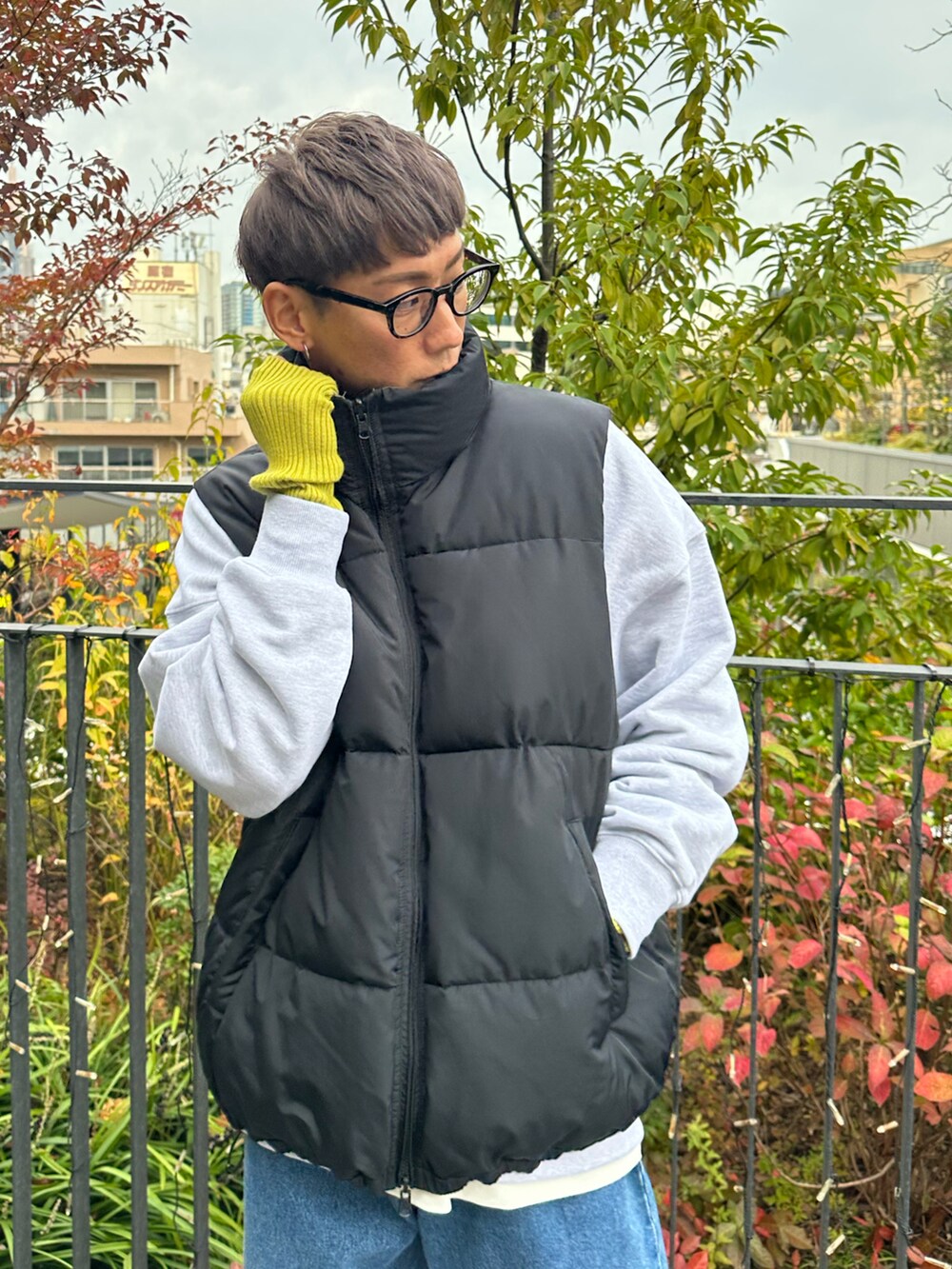 ブラック系のダウンベスト、ベージュ系のスウェット、ブルー系のデニムパンツを着用したメンズの秋コーディネートの5枚目の写真