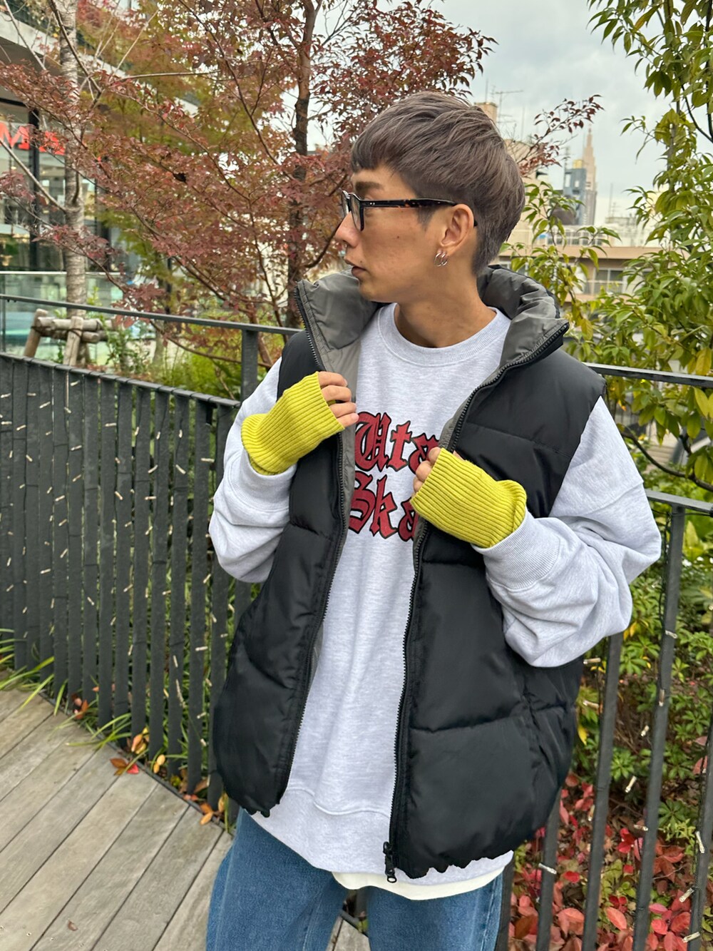 ブラック系のダウンベスト、ベージュ系のスウェット、ブルー系のデニムパンツを着用したメンズの秋コーディネートの4枚目の写真