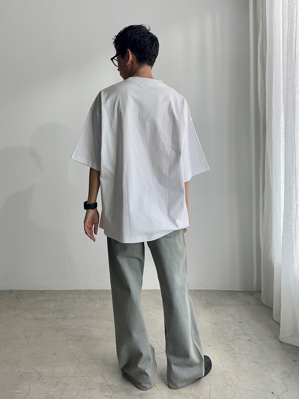 ブラック系のスニーカー、ブルー系のデニムパンツ、ホワイト系のTシャツ/カットソーを着用したメンズの夏コーディネートの3枚目の写真
