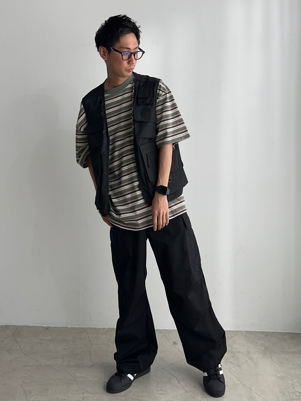 ブラック系のカーゴパンツ、ブラック系のベスト、ブラック系のスニーカーを着用したメンズの夏コーディネートの2枚目の写真