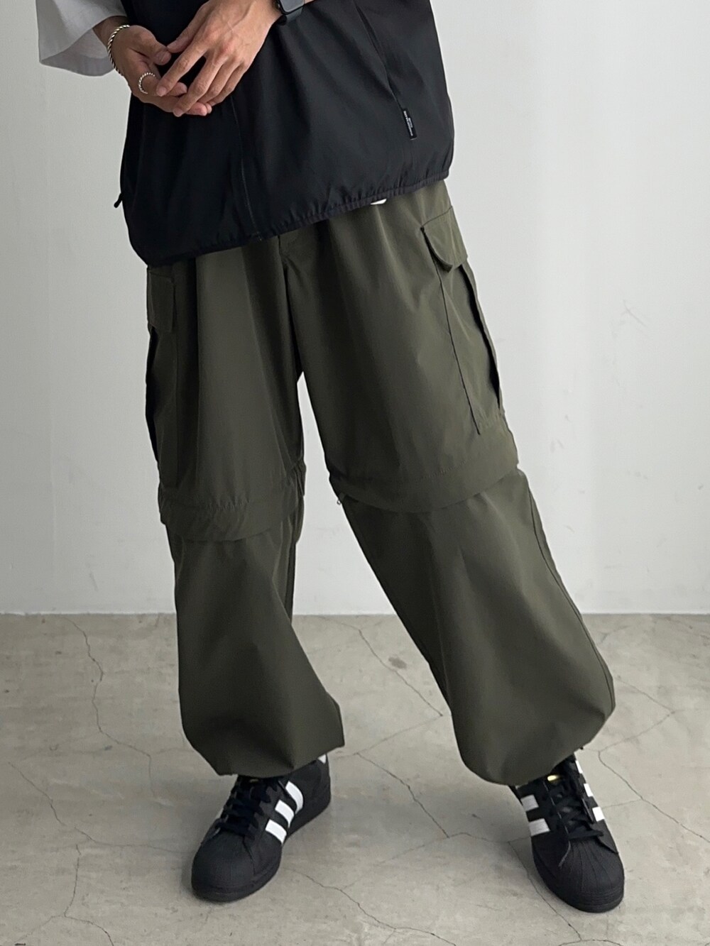 ホワイト系のTシャツ/カットソー、ブラック系のベスト、ブラック系のスニーカーを着用したメンズの夏コーディネートの3枚目の写真