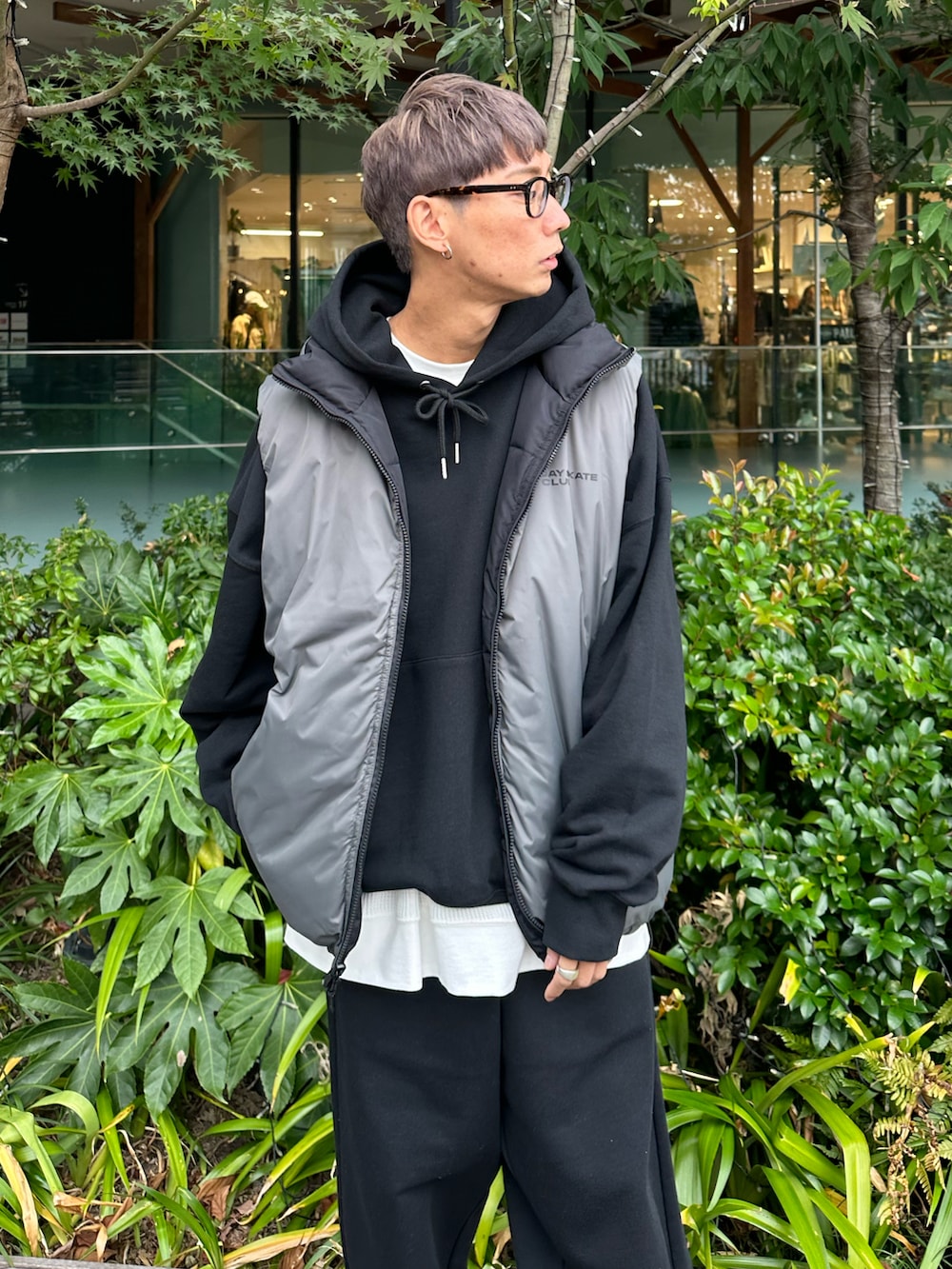 ブラック系のダウンベスト、ブラック系のパーカー、ホワイト系のスニーカーを着用したメンズの秋コーディネートの4枚目の写真