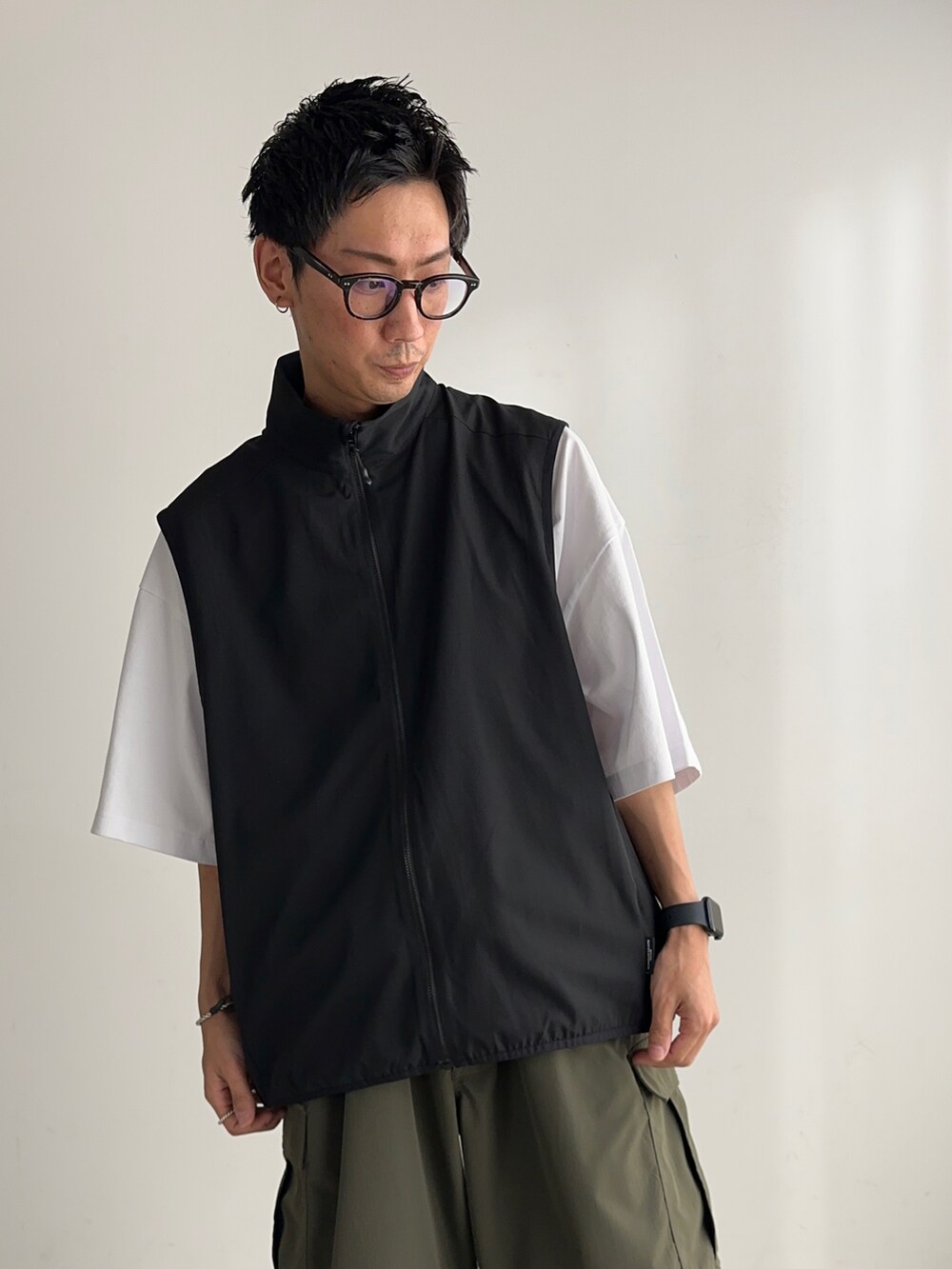 ホワイト系のTシャツ/カットソー、ブラック系のベスト、ブラック系のスニーカーを着用したメンズの夏コーディネートの4枚目の写真