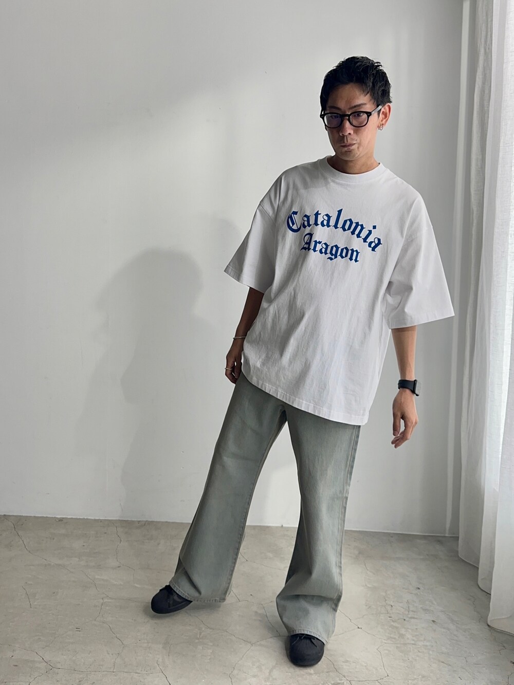 ブラック系のスニーカー、ブルー系のデニムパンツ、ホワイト系のTシャツ/カットソーを着用したメンズの夏コーディネートの2枚目の写真