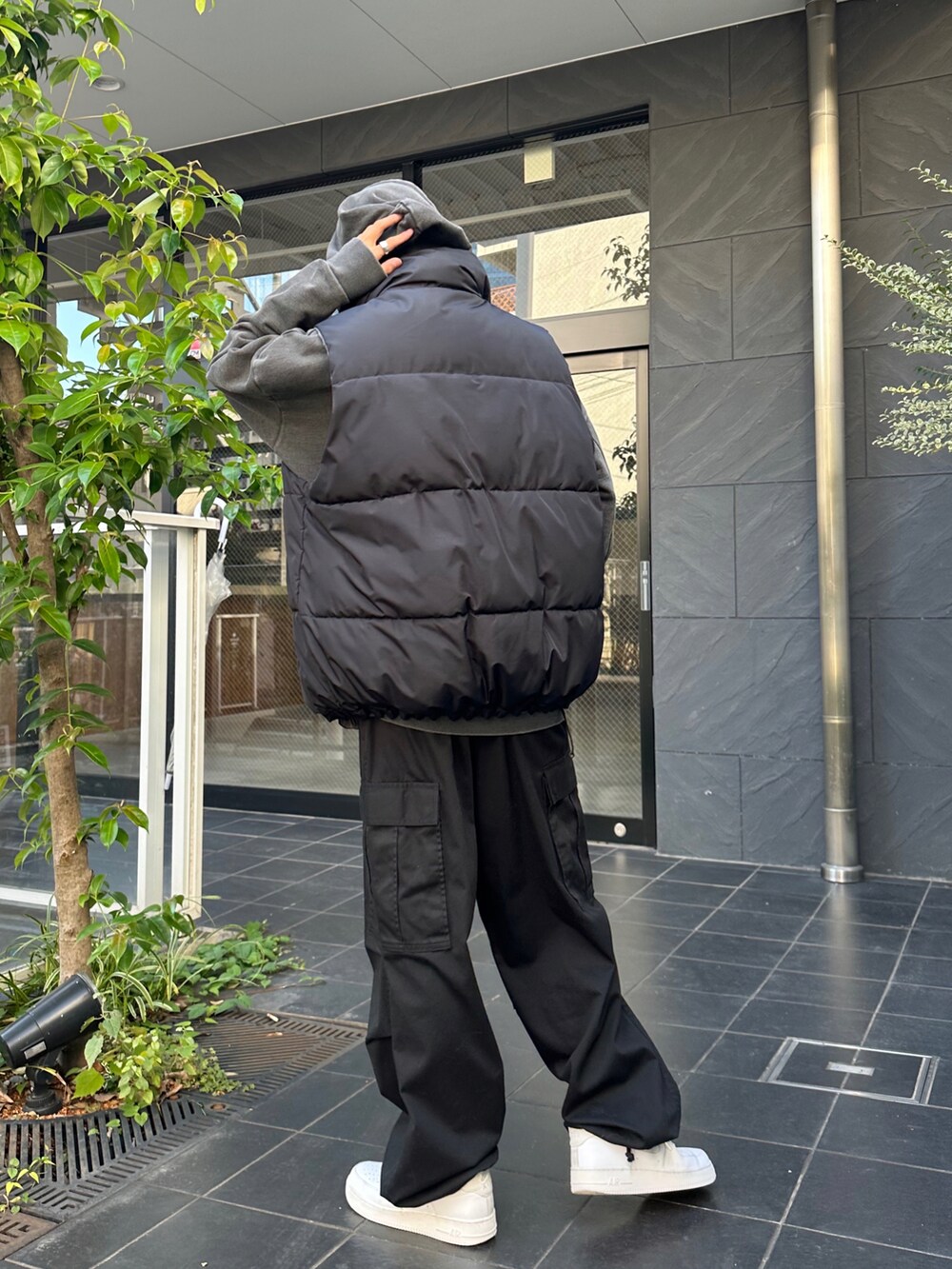 ブラック系のダウンベスト、ブラック系のカーゴパンツ、ホワイト系のスニーカーを着用したメンズの秋コーディネートの4枚目の写真