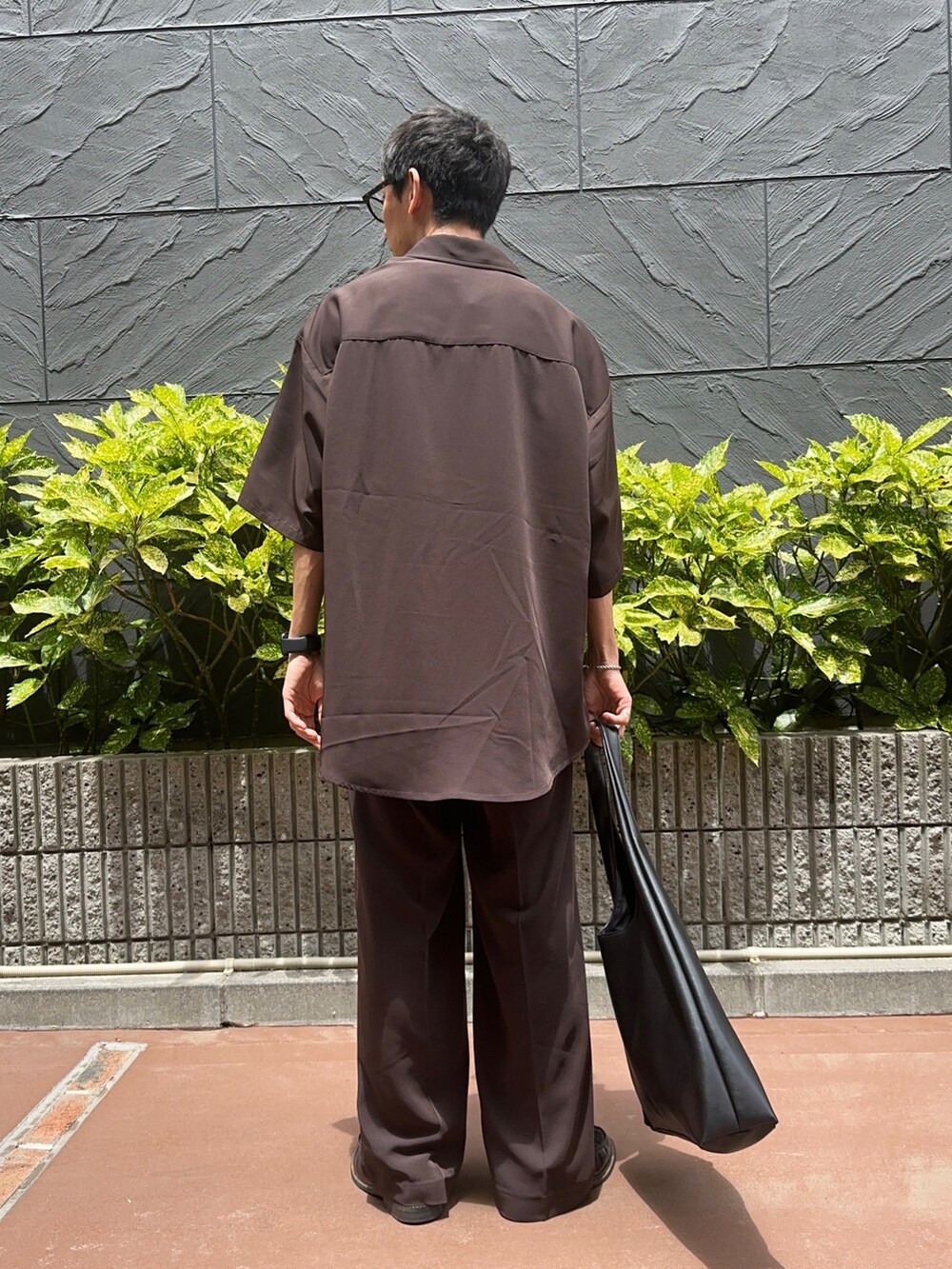 ブラック系のトートバッグ、ホワイト系のTシャツ/カットソー、ブラウン系のシャツ/ブラウスを着用したメンズの夏コーディネートの3枚目の写真