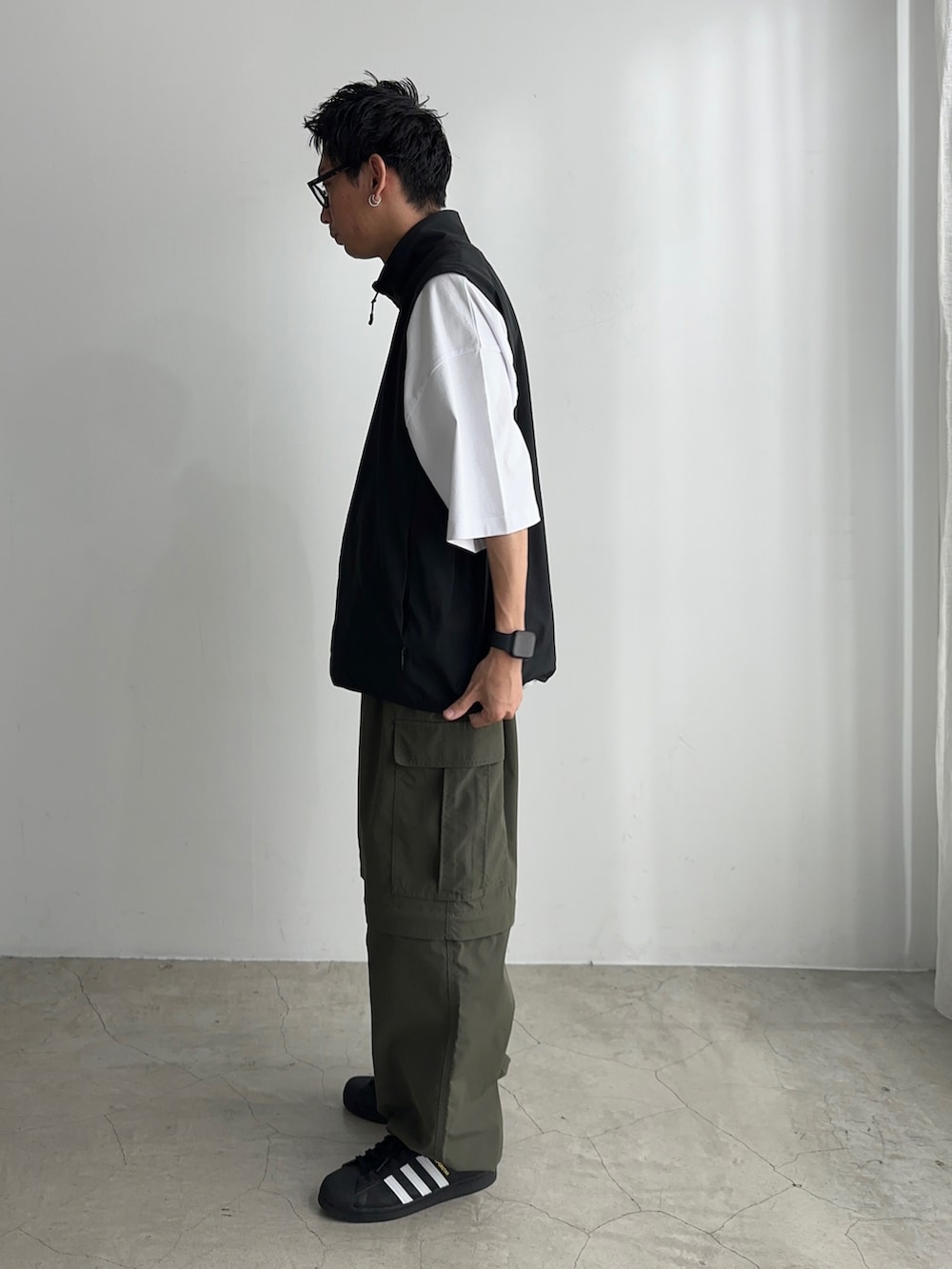 ホワイト系のTシャツ/カットソー、ブラック系のベスト、ブラック系のスニーカーを着用したメンズの夏コーディネートの2枚目の写真