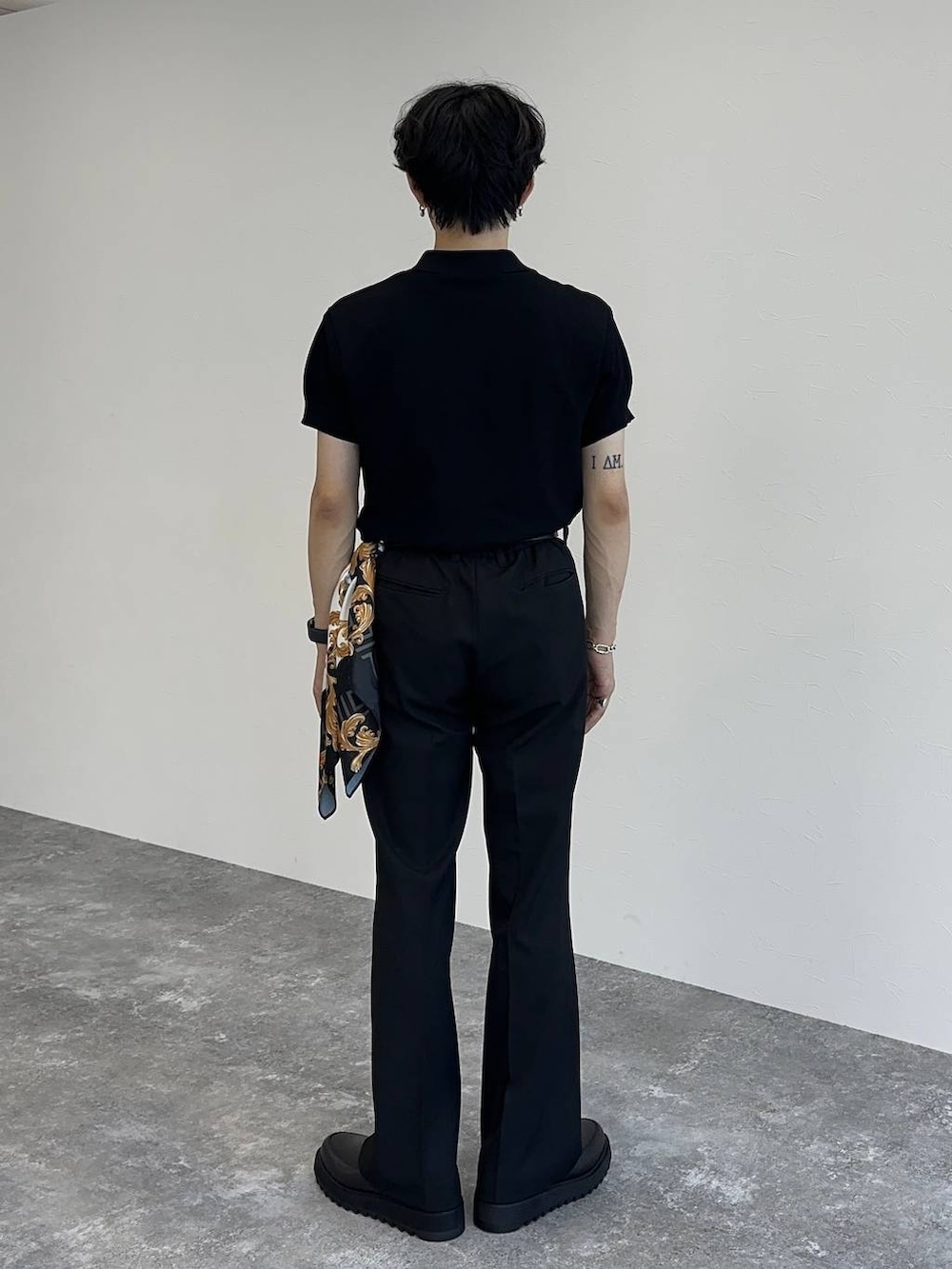 ブラック系のポロシャツ、ブラック系のスラックス、ブラック系のドレスシューズを着用したメンズの夏コーディネートの3枚目の写真