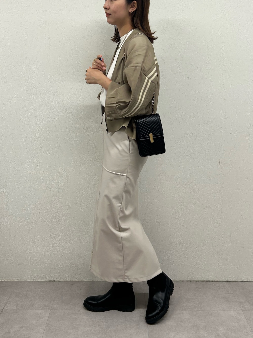 ベージュ系のブルゾン、ホワイト系のスカート、ブラック系のショルダーバッグを着用したレディースの秋コーディネートの2枚目の写真