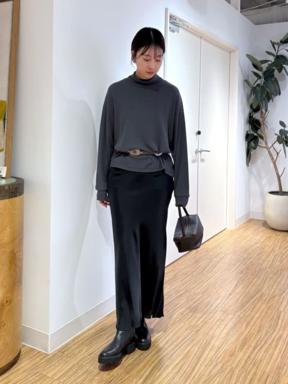 ブラック系のスカート、ブラウン系のハンドバッグ、ブラック系のブーツを着用したレディースの秋コーディネートの2枚目の写真