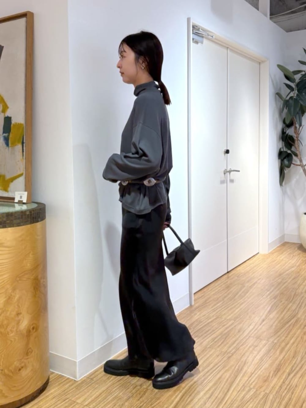 ブラック系のスカート、ブラウン系のハンドバッグ、ブラック系のブーツを着用したレディースの秋コーディネートの3枚目の写真