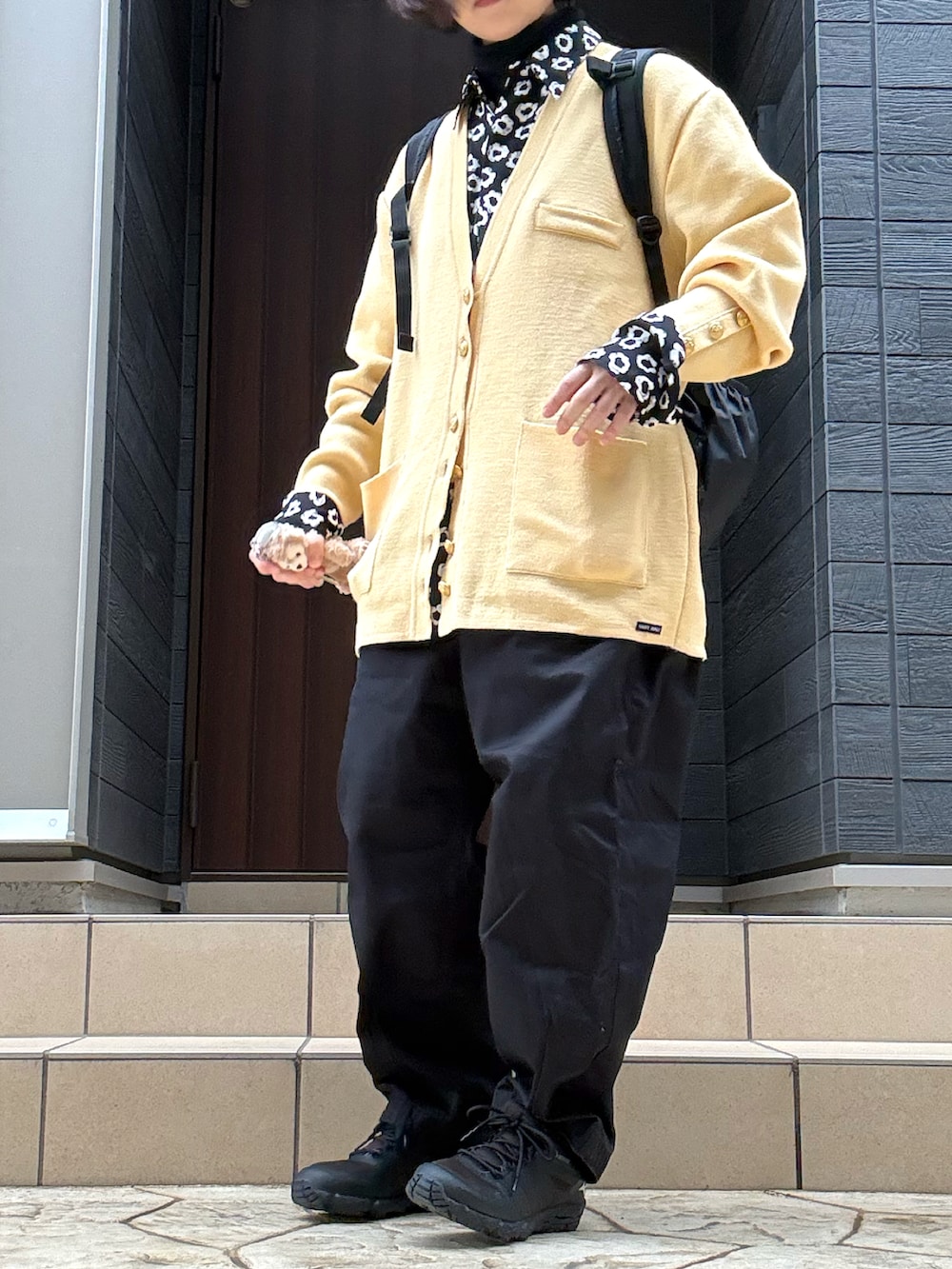 ホワイト系のチノパンツ、イエロー系のニット/セーター、ブラック系のシャツ/ブラウスを着用したレディースの春コーディネートの2枚目の写真