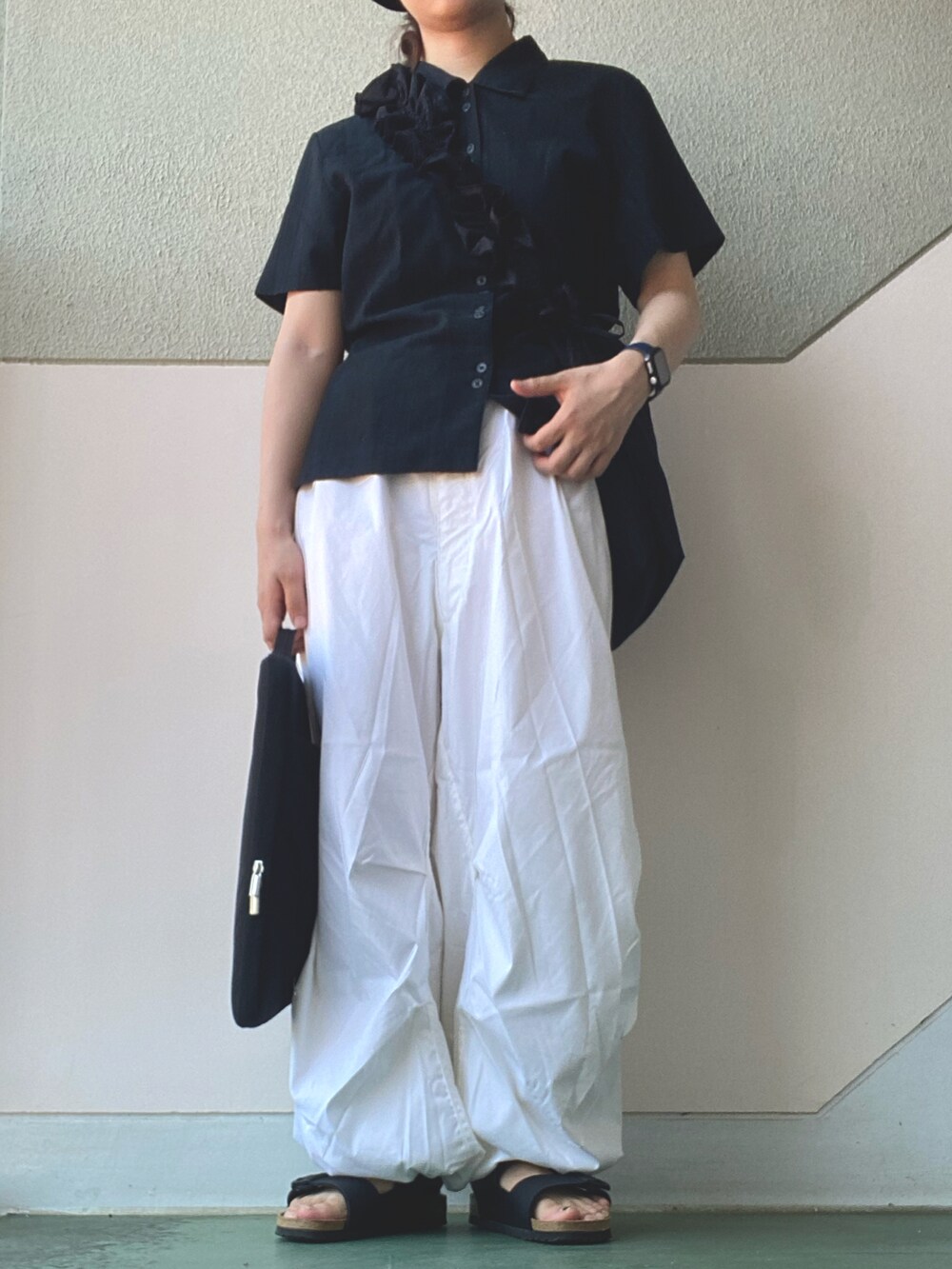 ブラック系のシャツ/ブラウス、ホワイト系のパンツ、ブラック系のサンダルを着用したレディースの夏コーディネートの2枚目の写真