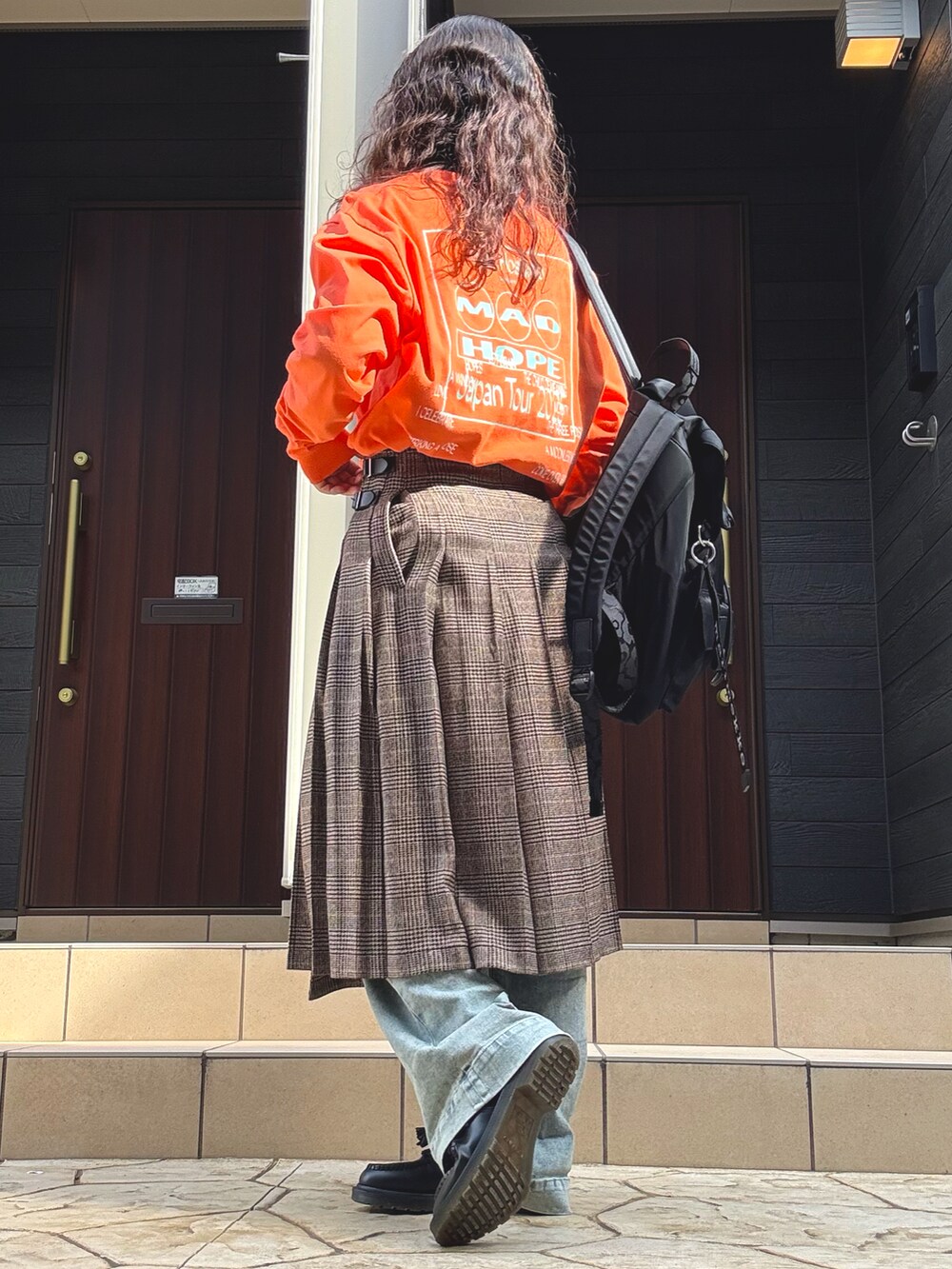 ブラウン系のスカート、ブラック系のローファー、ブルー系のデニムパンツを着用したレディースの秋コーディネートの2枚目の写真