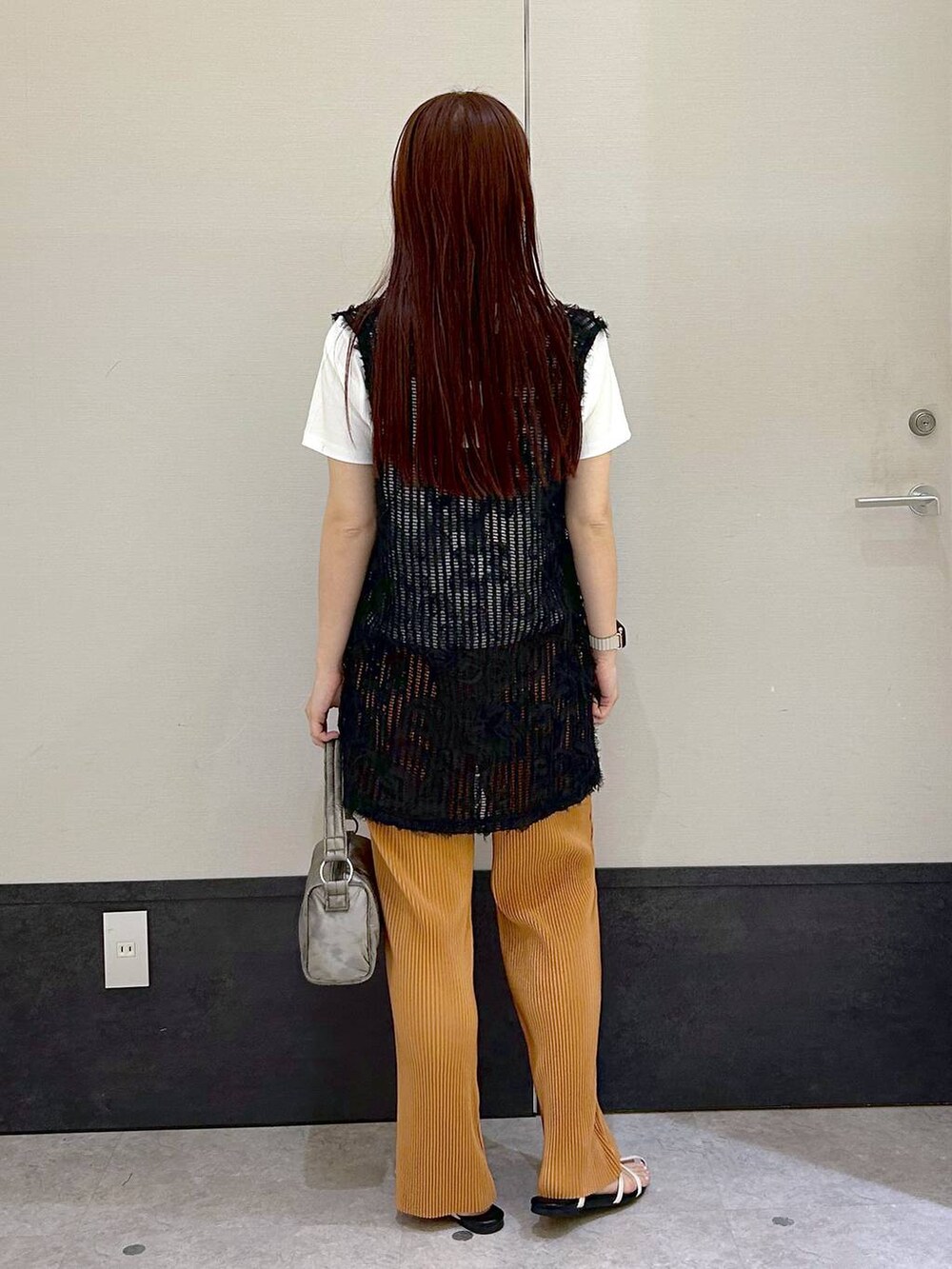 ブラック系のベスト、ホワイト系のTシャツ/カットソー、ホワイト系のサンダルを着用したレディースの春コーディネートの3枚目の写真