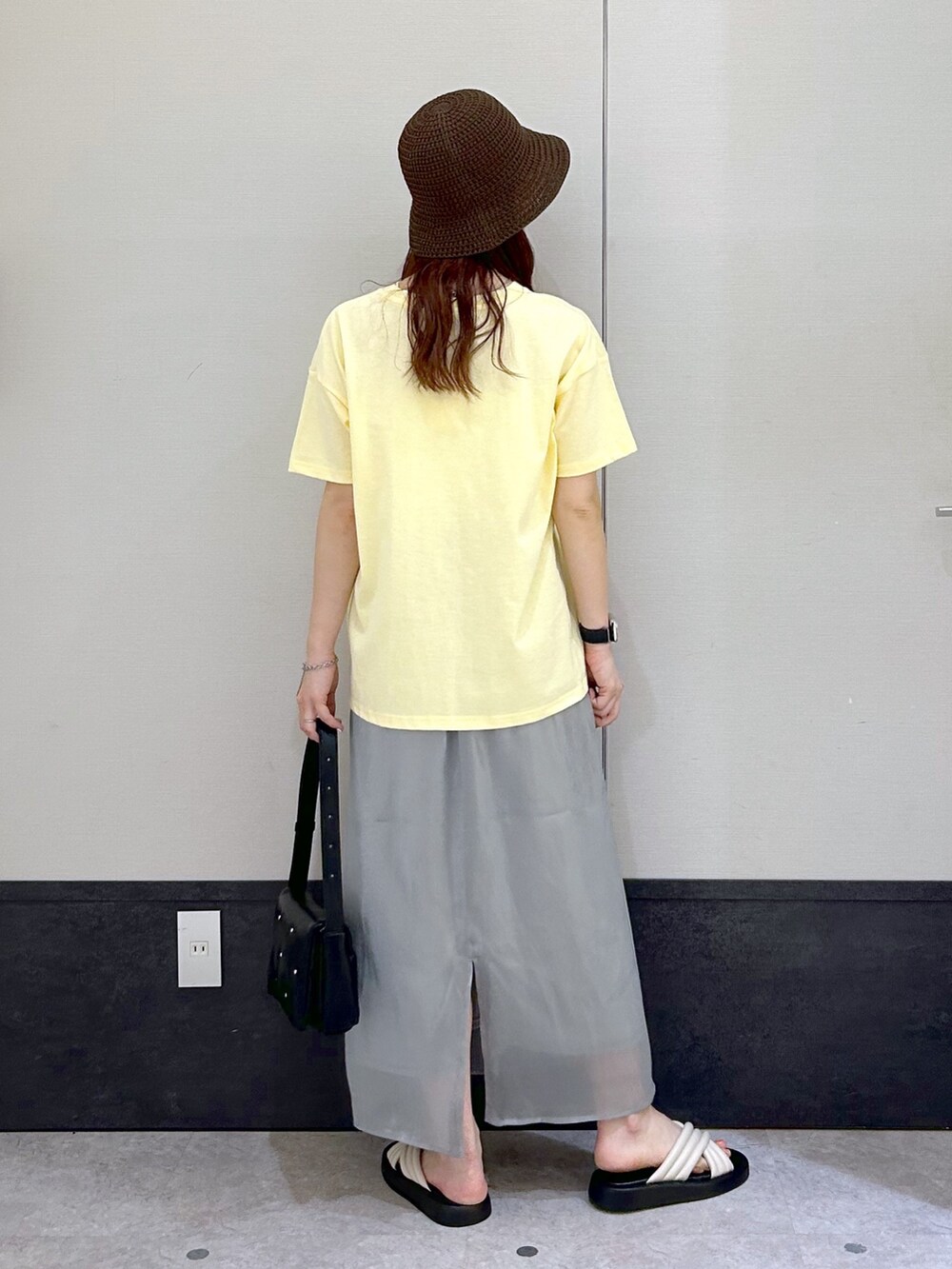 イエロー系のTシャツ/カットソー、グレー系のスカート、ブラック系のショルダーバッグを着用したレディースの春コーディネートの3枚目の写真