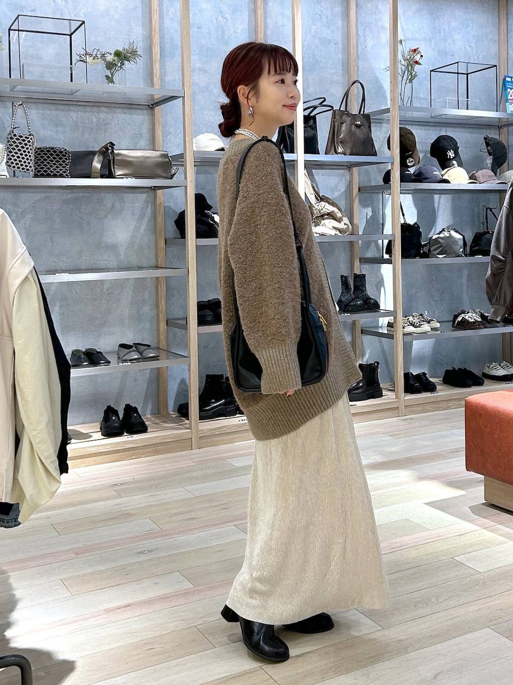 ブラウン系のカーディガン/ボレロ、ブラック系のブーツ、ブラック系のショルダーバッグを着用したレディースの秋コーディネートの2枚目の写真