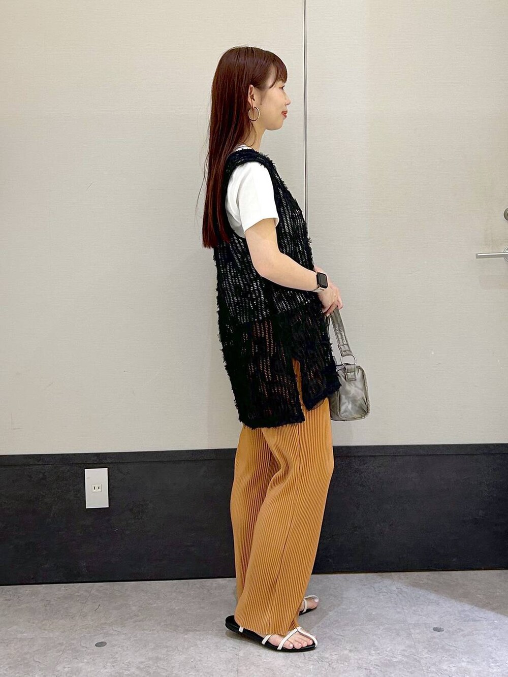 ブラック系のベスト、ホワイト系のTシャツ/カットソー、ホワイト系のサンダルを着用したレディースの春コーディネートの2枚目の写真