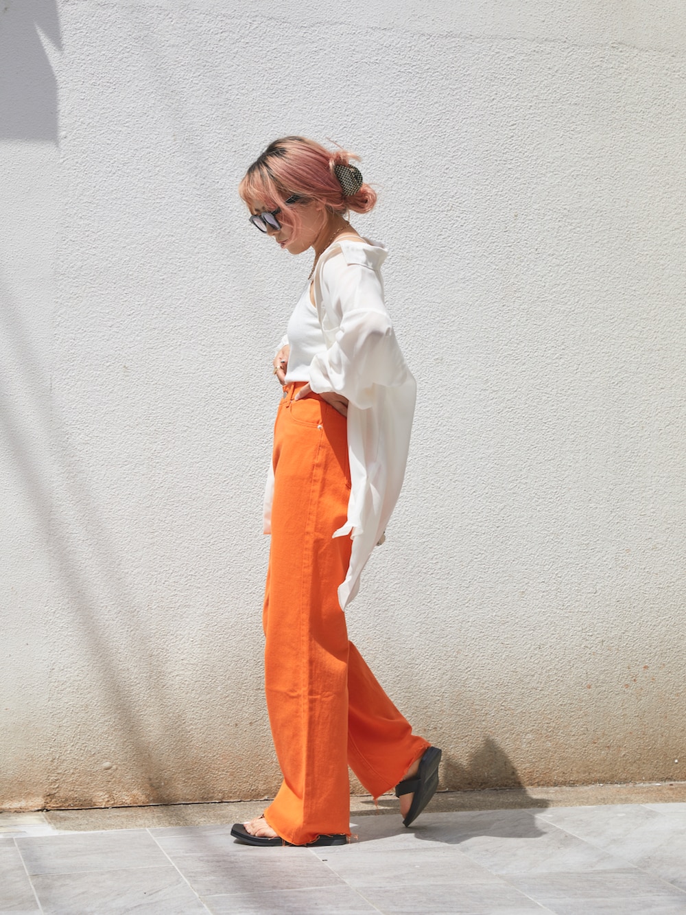 オレンジ系のデニムパンツ、ブラック系のシューズ、ホワイト系のシャツ/ブラウスを着用したレディースの春コーディネートの3枚目の写真