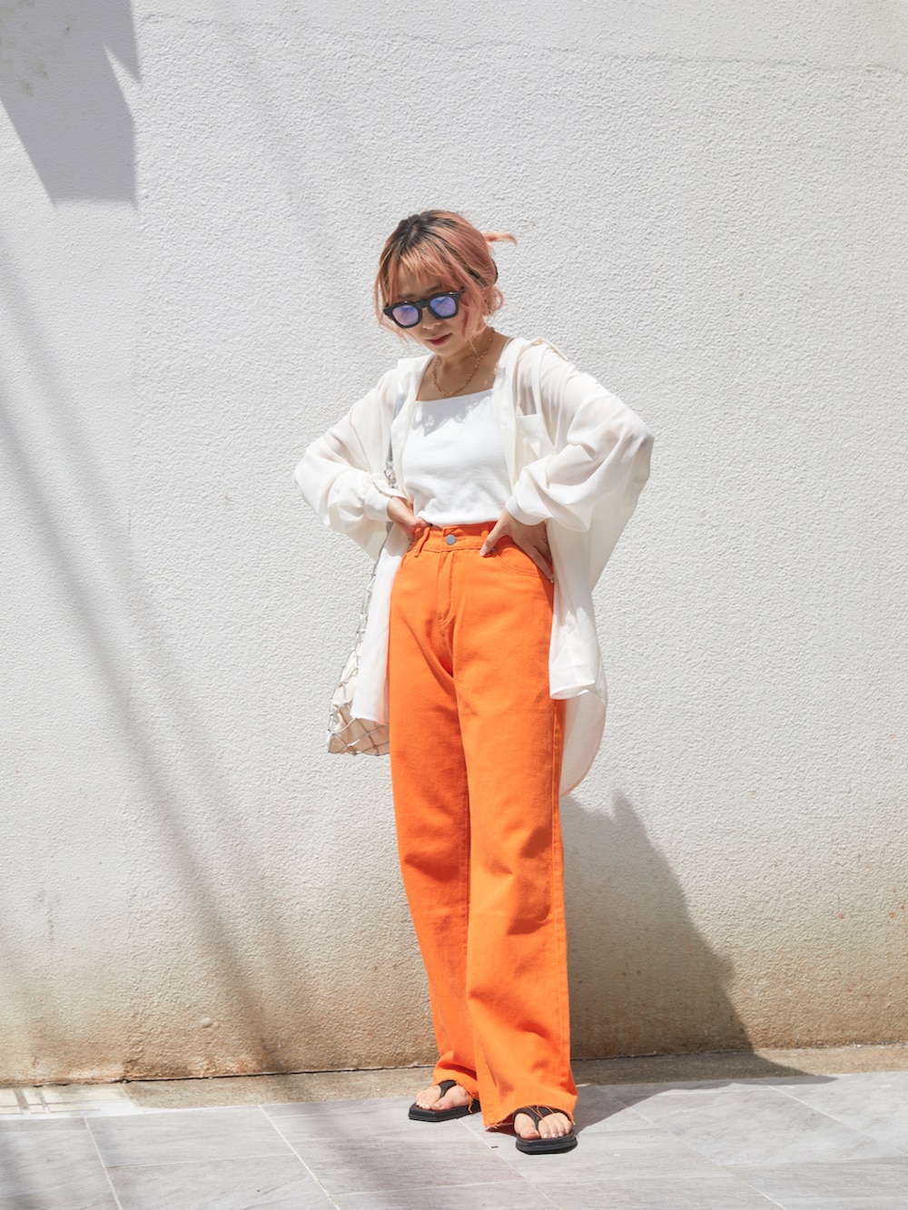 オレンジ系のデニムパンツ、ブラック系のシューズ、ホワイト系のシャツ/ブラウスを着用したレディースの春コーディネートの2枚目の写真