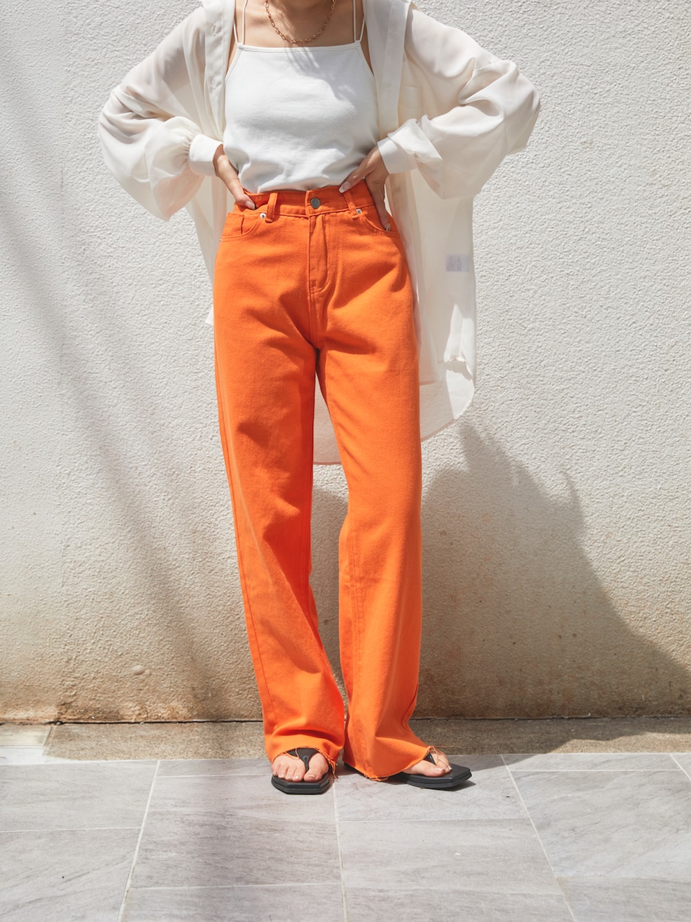 オレンジ系のデニムパンツ、ブラック系のシューズ、ホワイト系のシャツ/ブラウスを着用したレディースの春コーディネートの4枚目の写真