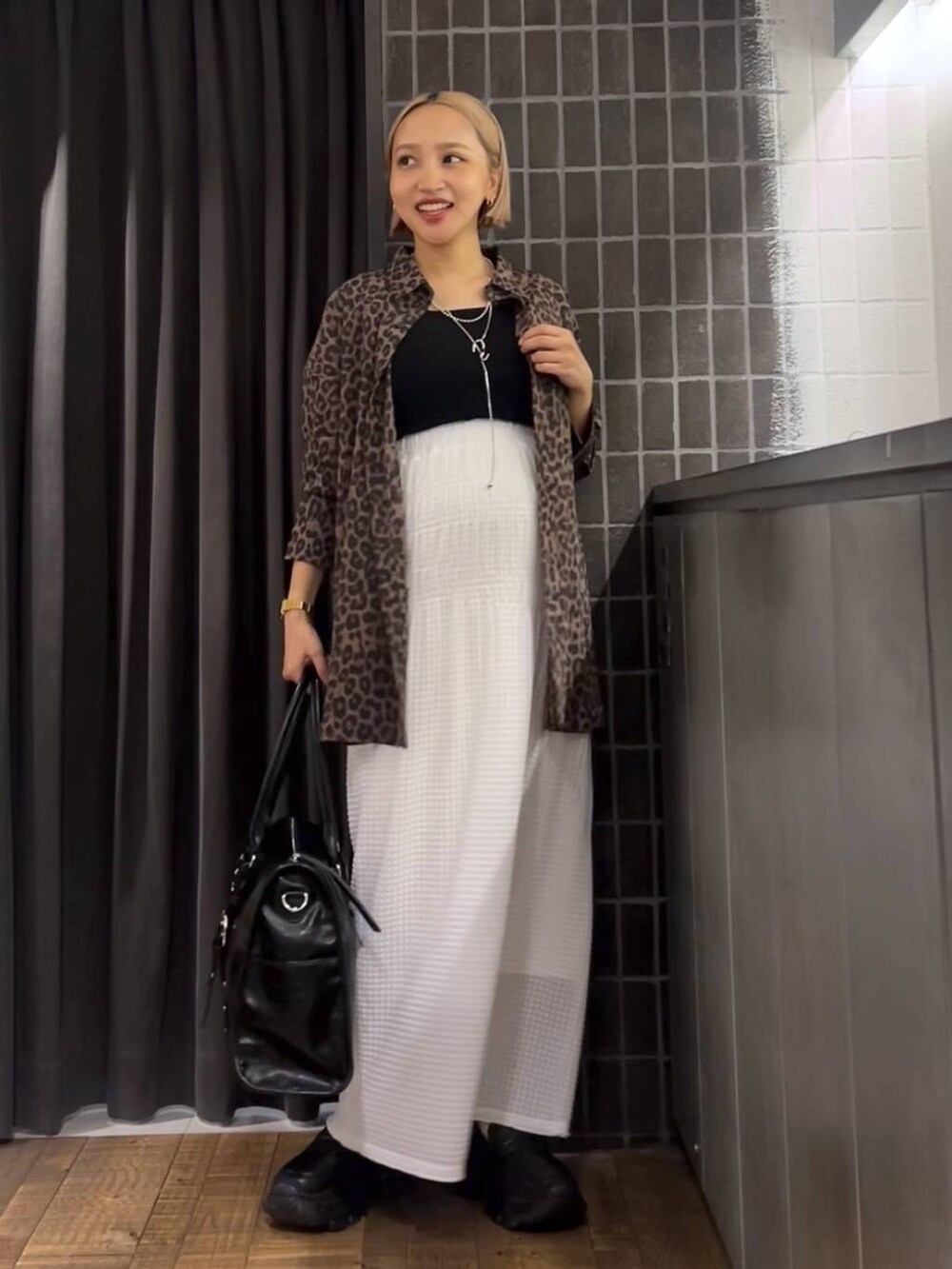 ホワイト系のスカート、ブラック系のローファー、ブラック系のタンクトップを着用したレディースの夏コーディネートの7枚目の写真