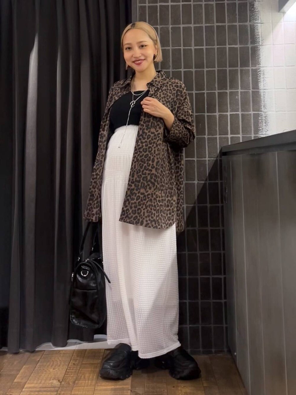 ホワイト系のスカート、ブラック系のローファー、ブラック系のタンクトップを着用したレディースの夏コーディネートの6枚目の写真