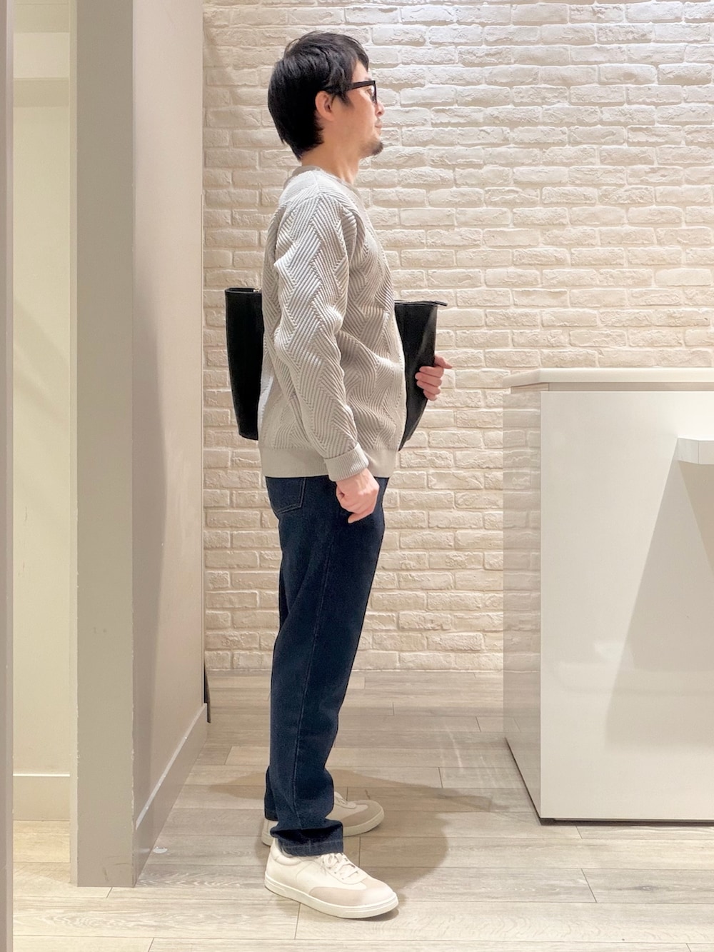 グレー系のニット/セーター、ブルー系のデニムパンツ、ブラック系のトートバッグを着用したメンズの冬コーディネートの5枚目の写真