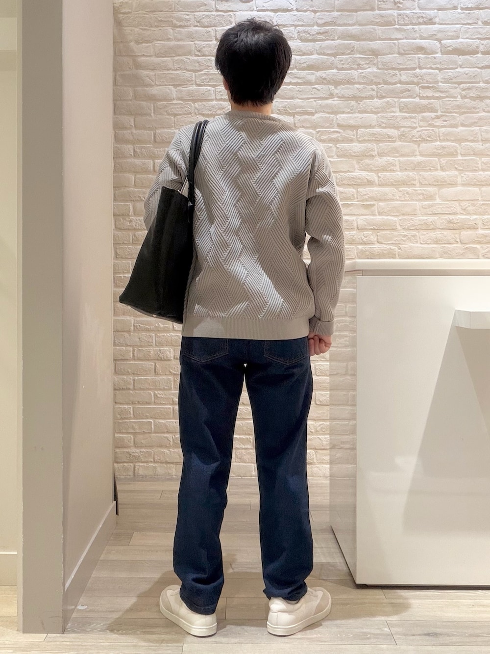 グレー系のニット/セーター、ブルー系のデニムパンツ、ブラック系のトートバッグを着用したメンズの冬コーディネートの6枚目の写真