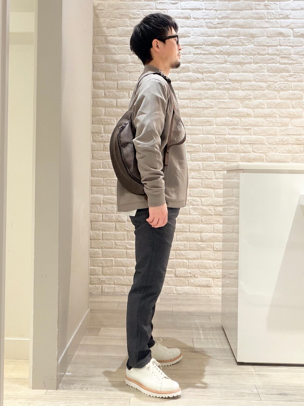 ブラウン系のブルゾン、ホワイト系のスニーカー、ホワイト系のTシャツ/カットソーを着用したメンズの冬コーディネートの4枚目の写真
