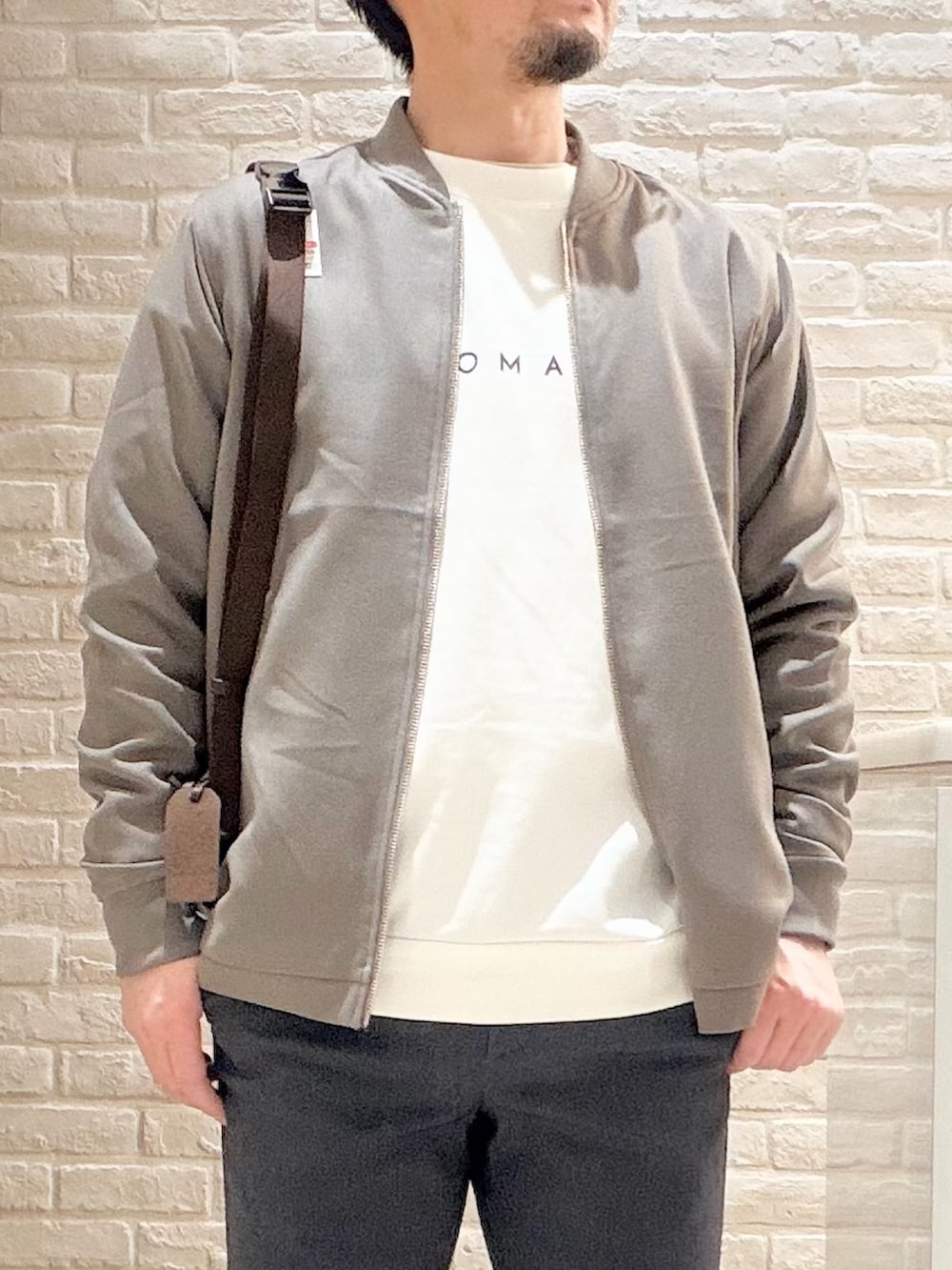 ブラウン系のブルゾン、ホワイト系のスニーカー、ホワイト系のTシャツ/カットソーを着用したメンズの冬コーディネートの2枚目の写真