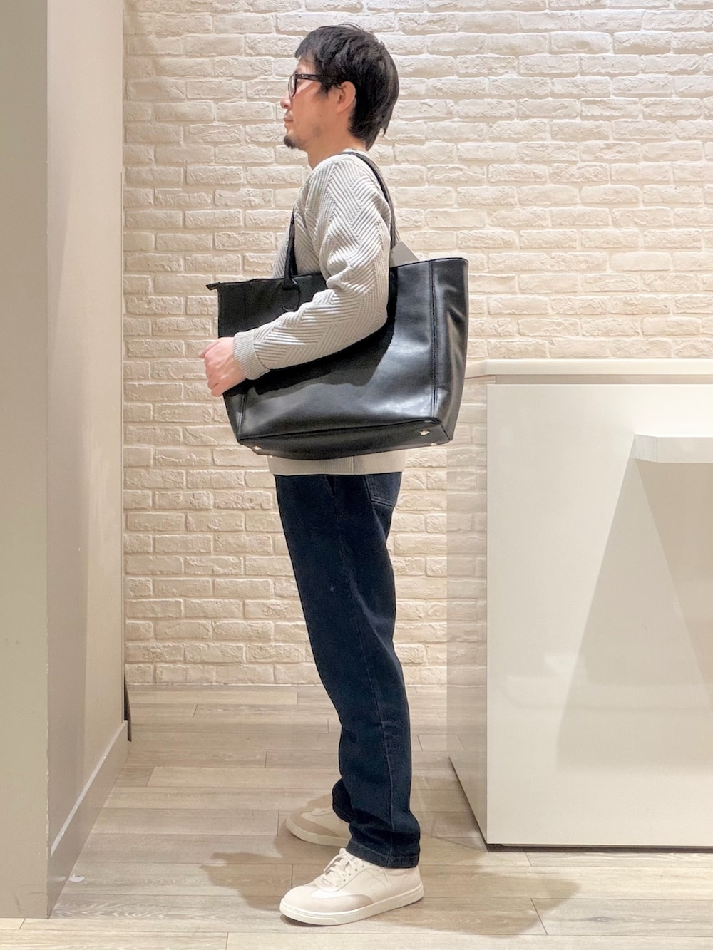 グレー系のニット/セーター、ブルー系のデニムパンツ、ブラック系のトートバッグを着用したメンズの冬コーディネートの7枚目の写真