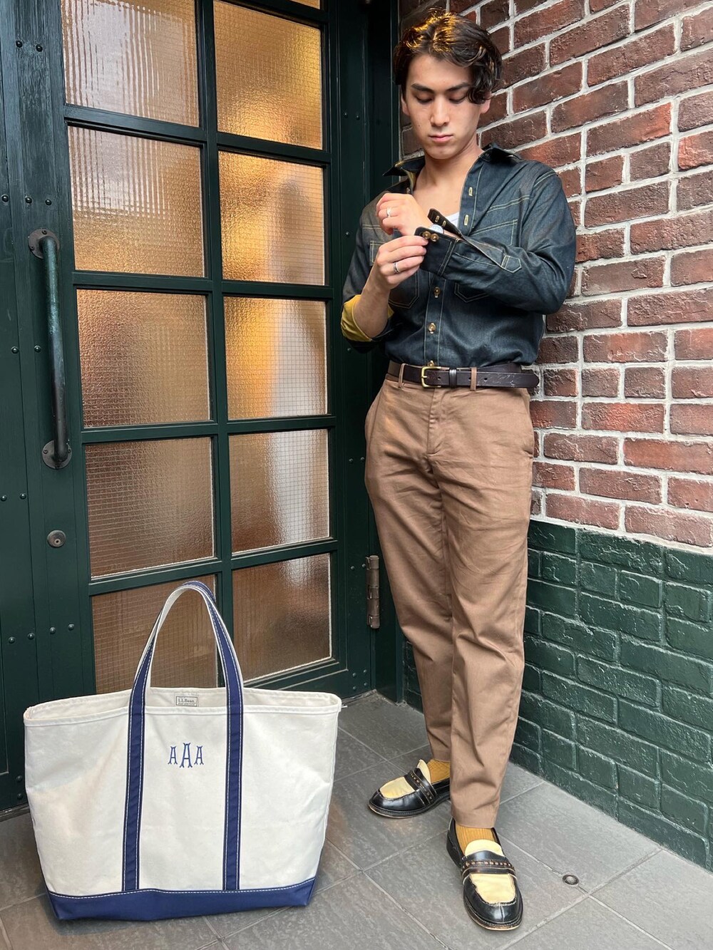 ブラウン系のパンツ、ホワイト系のトートバッグ、ブラウン系のベルトを着用したメンズの冬コーディネートの2枚目の写真