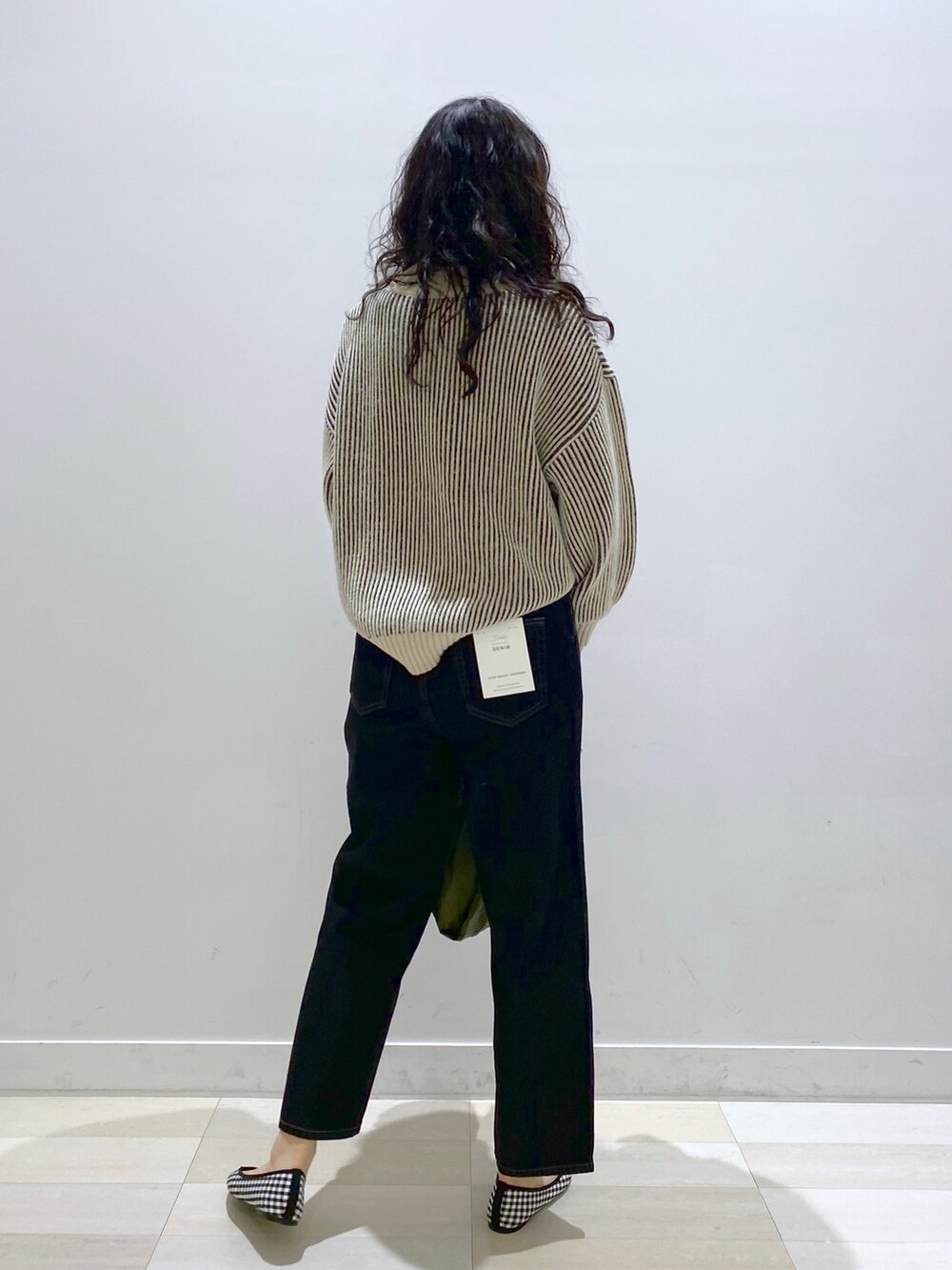 ブラウン系のエコバッグ/サブバッグ、ブラック系のデニムパンツ、グレー系のニット/セーターを着用したレディースの冬コーディネートの3枚目の写真