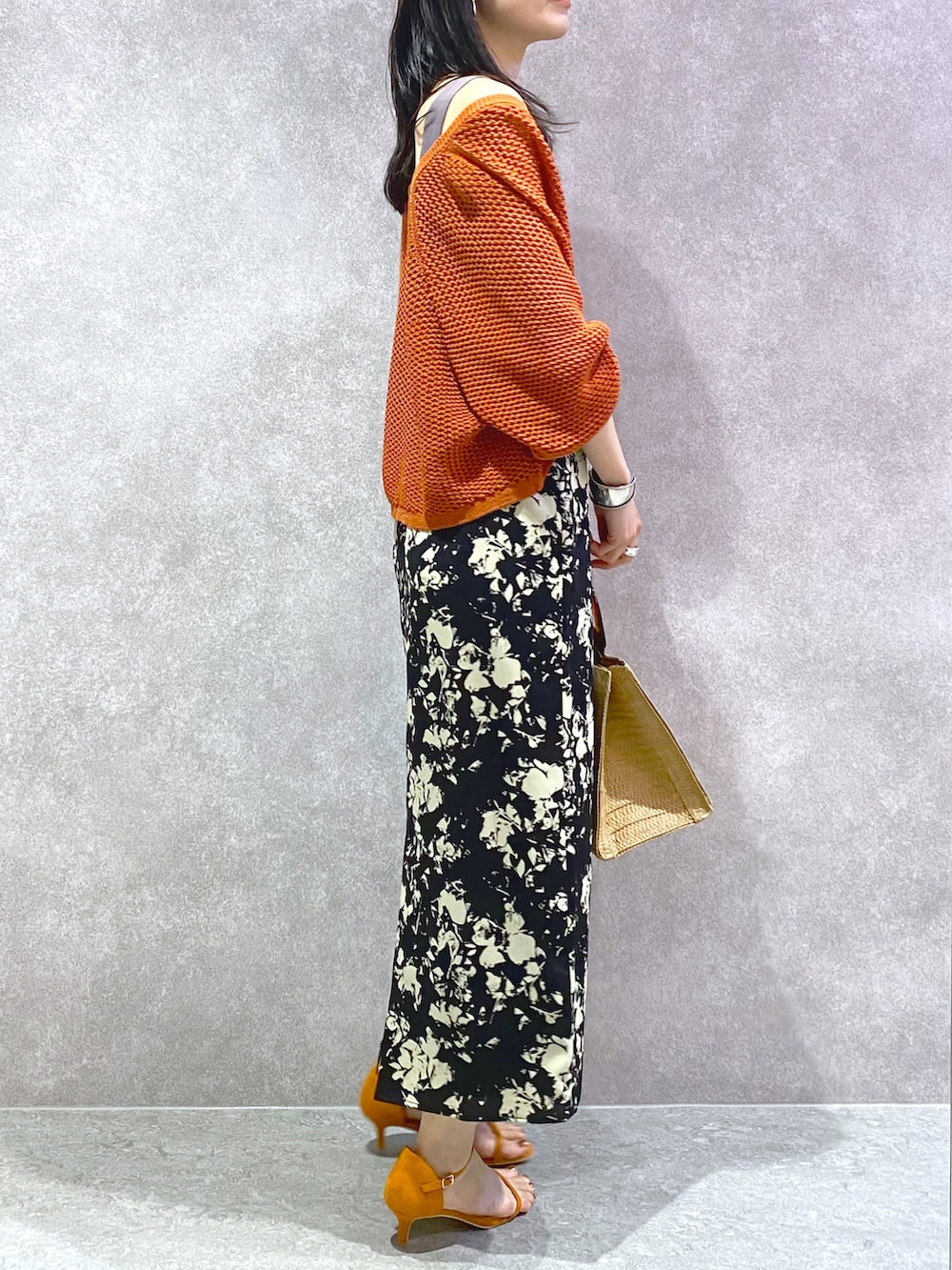 ベージュ系のかごバッグ、グレー系のタンクトップ、オレンジ系のカーディガン/ボレロを着用したレディースの春コーディネートの2枚目の写真