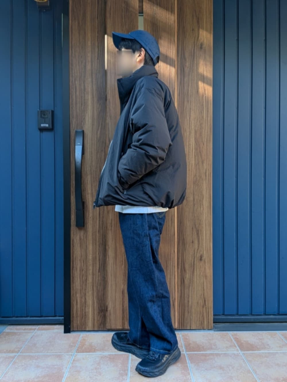 ブラック系のスニーカー、ブルー系のデニムパンツ、ブラック系のダウンジャケット/コートを着用したメンズの冬コーディネートの3枚目の写真