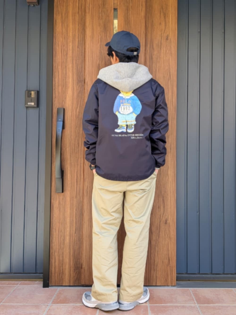 グレー系のスニーカー、ベージュ系のチノパンツ、ブルー系のナイロンジャケットを着用したメンズの冬コーディネートの3枚目の写真